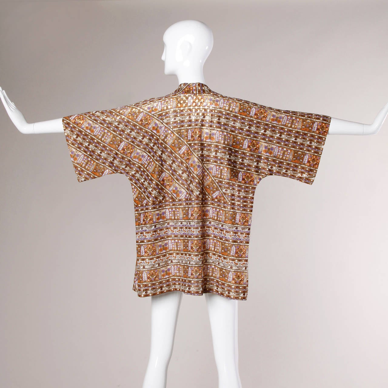 Egyptian-inspired vintage metallic kimono jacket by Mr. Blackwell.

Details:

Unlined
No Closure
Circa: 1970's
Estimated Size: Free
Color: Gold Metallic/ Lavender/ Rust/ White
Fabric: Not Marked
Label: Mr.