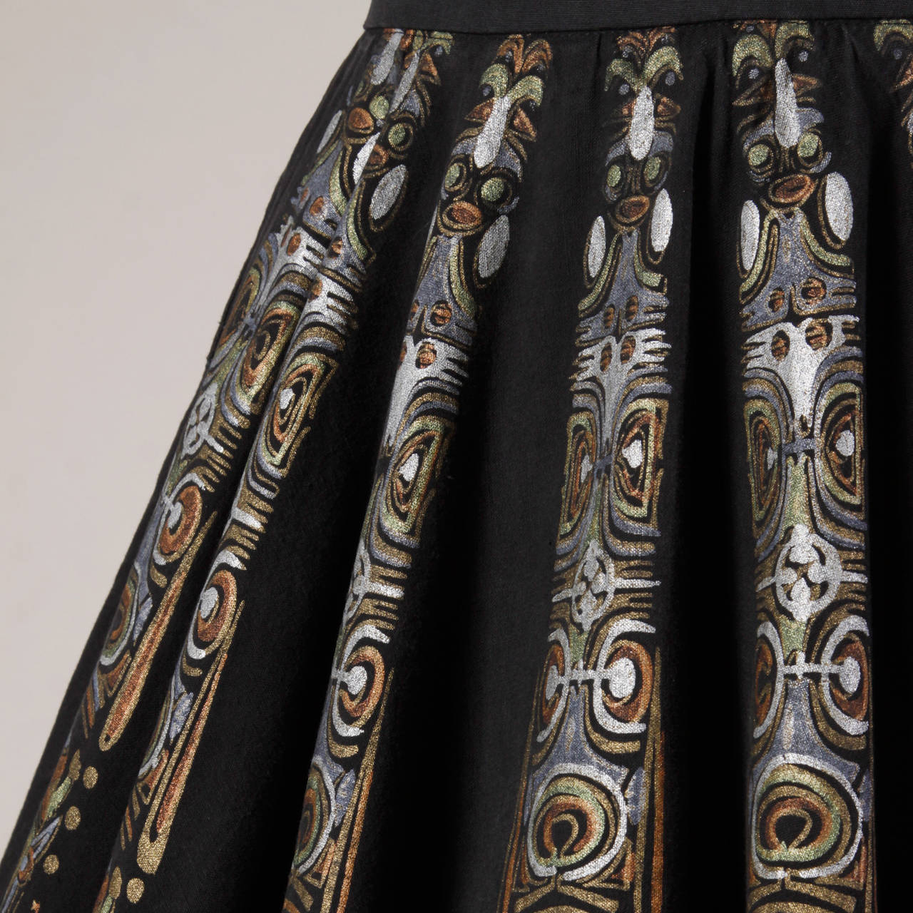 Stunning hand painted Mexican circle skirt from the 1950s. Intricate metallic design with Mayan style masks.

Details:

Unlined
Side Pockets
Side Metal Zip and Hook Closure
Marked Size: Not Marked
Estimated Size: Medium/ 27
Color: Black/