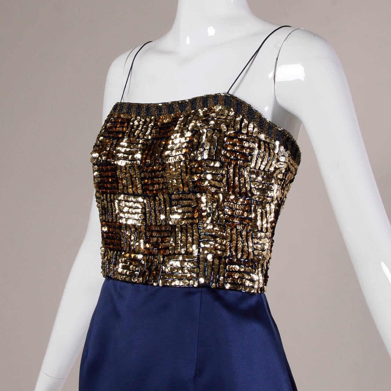 Vintage blue satin cocktail dress with metallic gold sequin and beaded bodice by Bill Blass.

PLEASE NOTE: There is some overall wear and slight loss of metallic finish to some of the sequins. This dress has been priced