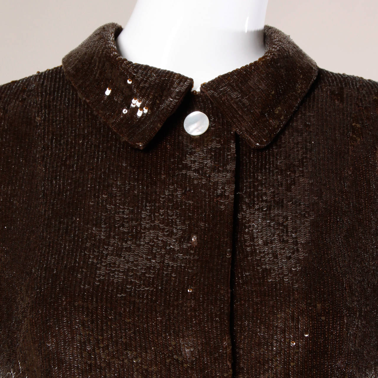 Chocolate brown silk short sleeved top or jacket encrusted in tiny sequins by Oscar de la Renta. Satin lining and two decorative pearl buttons.

Details:

Fully Lined
Front Snap Closure
Marked Size: 6
Estimated Size: Small
Color: