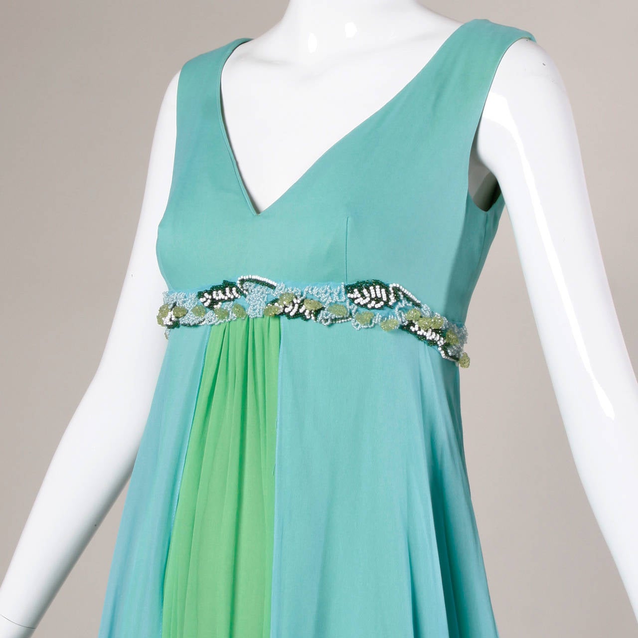 Unworn with the original tags still attached, 1971 green and blue color block gown with a beaded empire waist.

Details:

Fully Lined
Back Metal Zip and Hook Closure
Marked Size: 12
Estimated Size: Medium
Color: Sky Blue/ Bright Green
