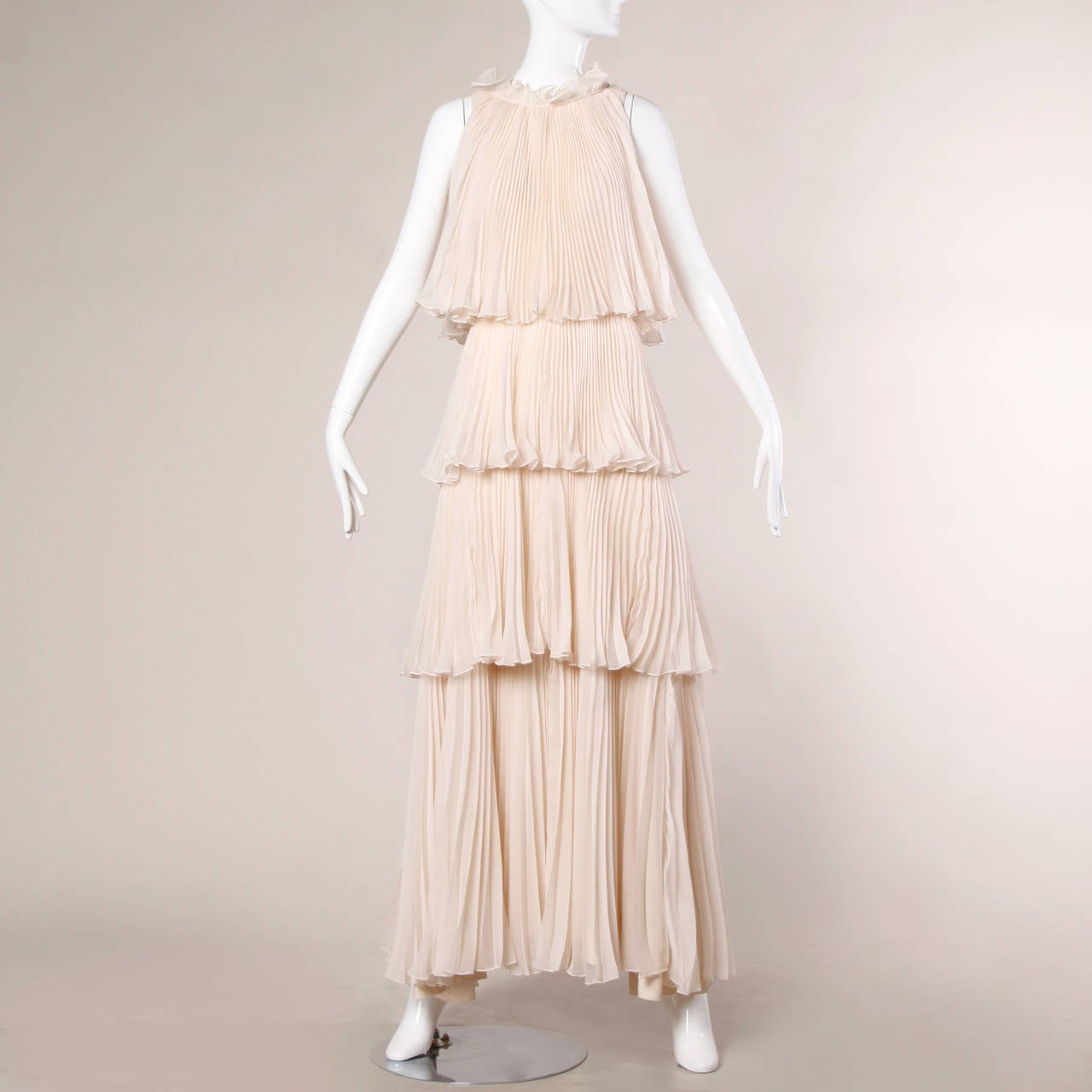 Incredible blush tiered accordion pleated maxi dress by English designer Jean Varon. This dress has a huge sweep and features a lot of beautiful fabric! Sleeveless sleeves and ruffled neckline.

Details:

Unlined
Back Zip Hook and Tie