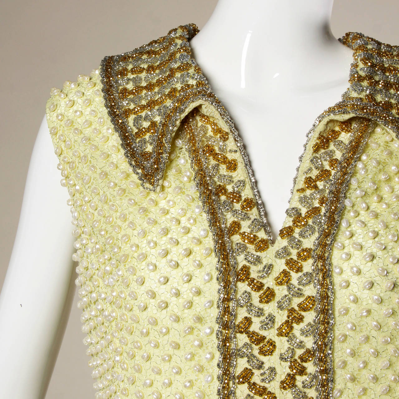 Pastel yellow lace shift dress entirely encrusted in tiny pearl beads. Structured beaded collar and sleeveless sleeves.

Details:

Fully Lined
Back Metal Zip and Hook Closure
Marked Size: Not Marked
Estimated Size: Medium
Color: Iridescent