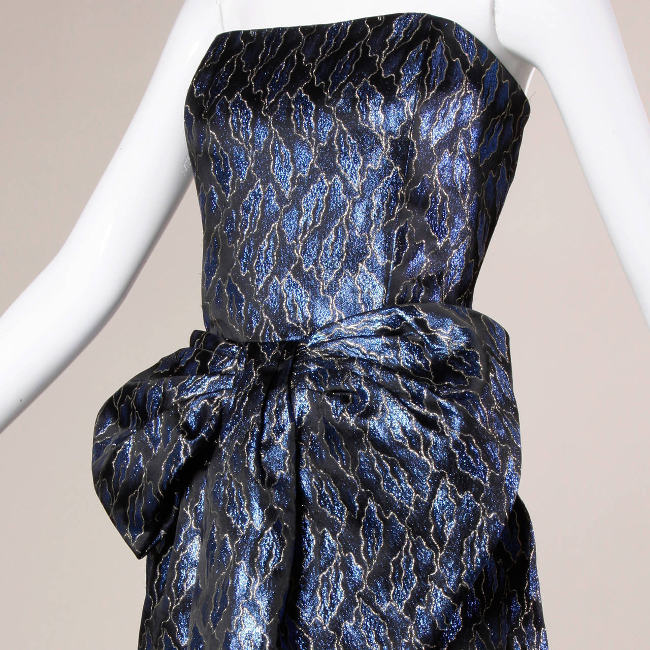 Reduced from $600. Vintage blue and black metallic brocade strapless gown with an origami bow fold at the waist. By Victor Costa.

Details:

Partially Lined
Back Zip and Hook Closure
Marked Size: 14
Estimated Size: M-L
Color: Metallic