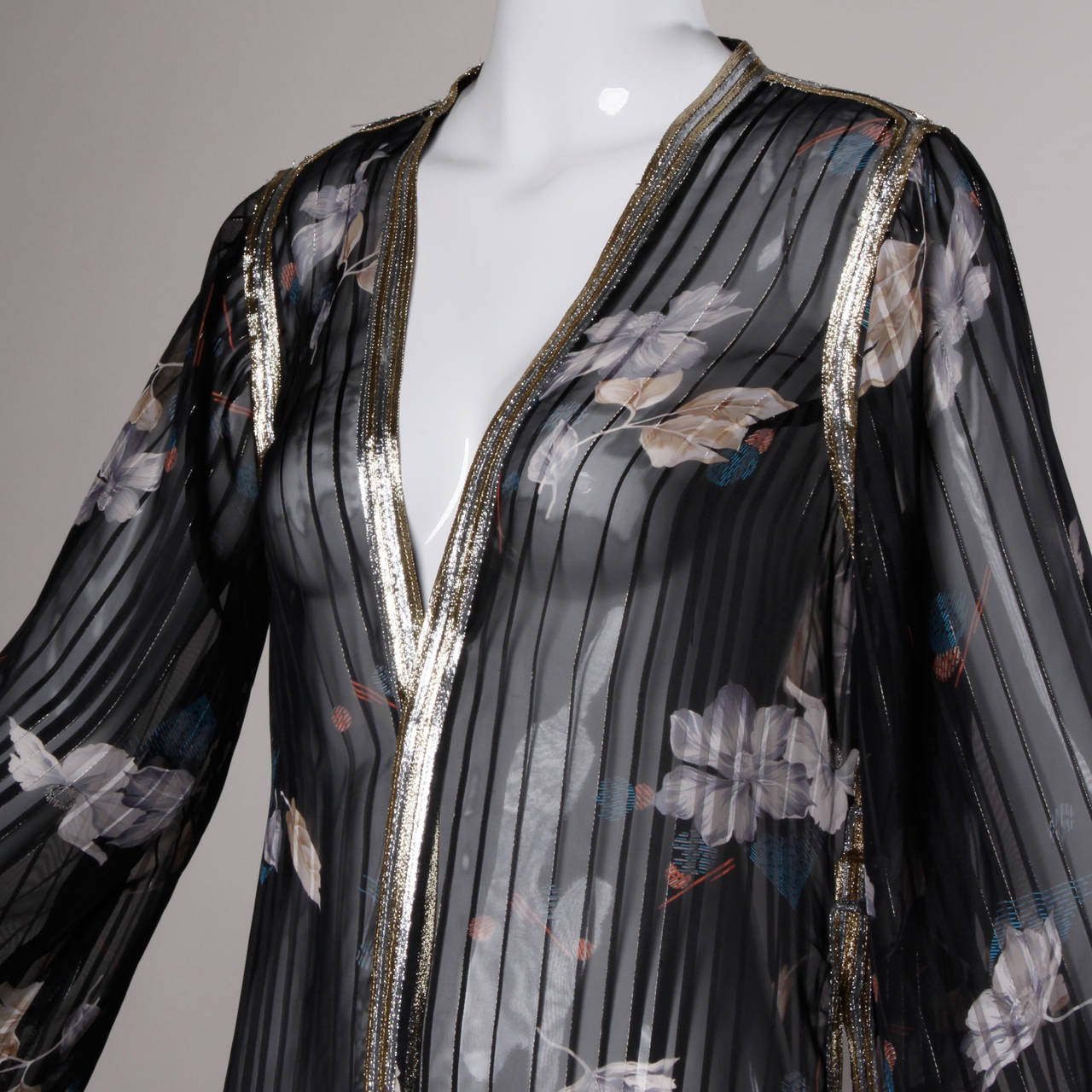 Gorgeous vintage sheer duster with metallic trim and a floral print. The fabric feels like it might be a silk-rayon blend but it is not marked. Long length and side slits.

Details:

Unlined
No Closure
Marked Size: Not Marked
Estimated Size: