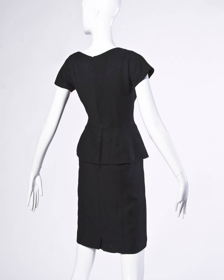 Chic 1950s black wool blend cocktail dress with a petal peplum. Fitted bodice and scoop neck.

Details:

Estimated Size: S-M
Partially Lined
Back Metal Zip and Hook Closure
Color: Black
Fabric: Not Marked
Label: GG