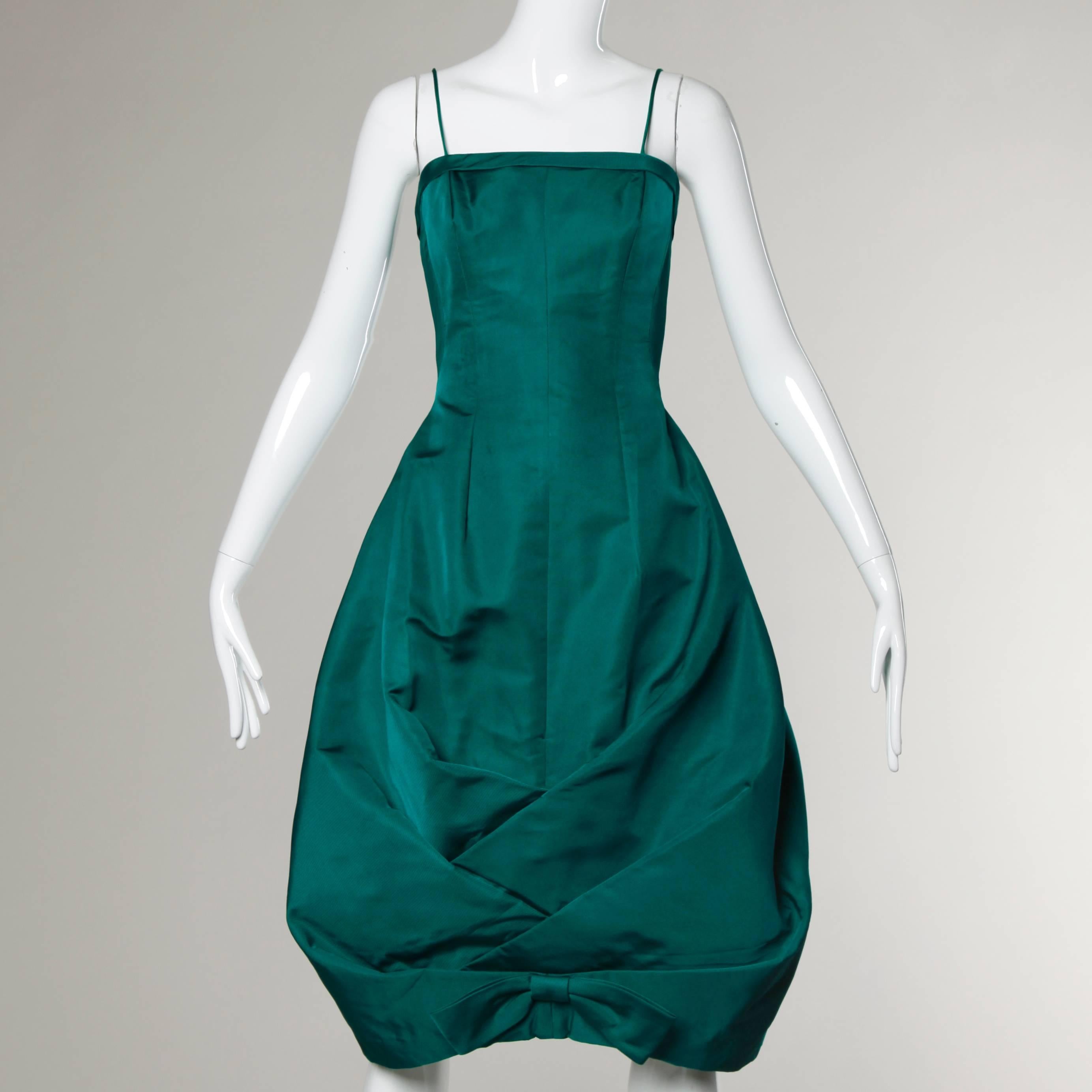 Stunning and unique emerald green silk taffeta dress with an origami bubble hem by Suzy Perette. Bow detail at the bottom and hourglass silhouette.

Details:

Unlined
Back Metal Zip and Hook Closure
Marked Size: 8
Estimated Size:
