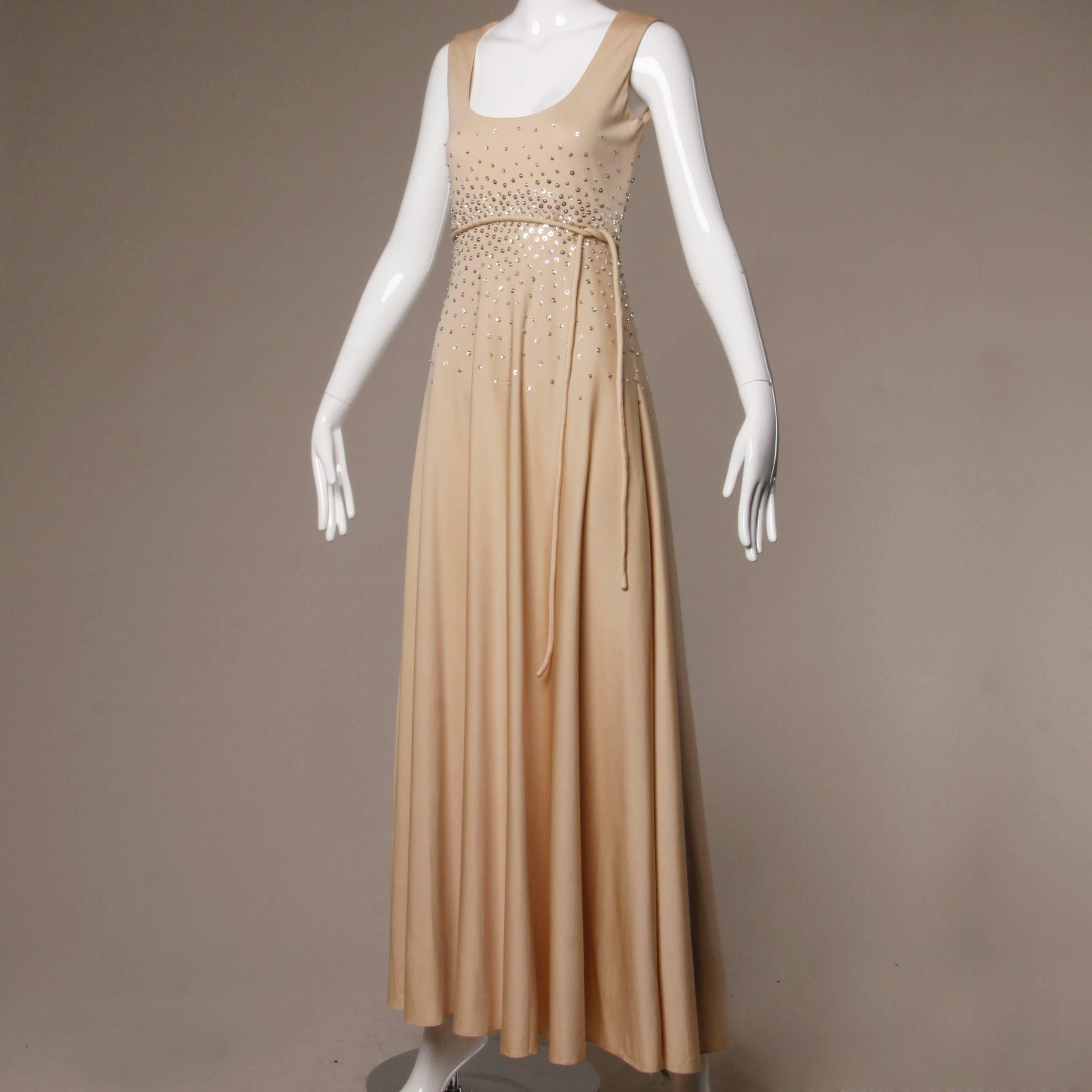 Stunning vintage nude jersey knit maxi dress with an empire waist and silver sequins. 

Details:

Fully Lined
Matching Belt
Back Metal Zip and Hook Closure
Marked Size: Not Marked
Estimated Size: S-M
Color: Beige/ Silver Metallic 
Fabric: