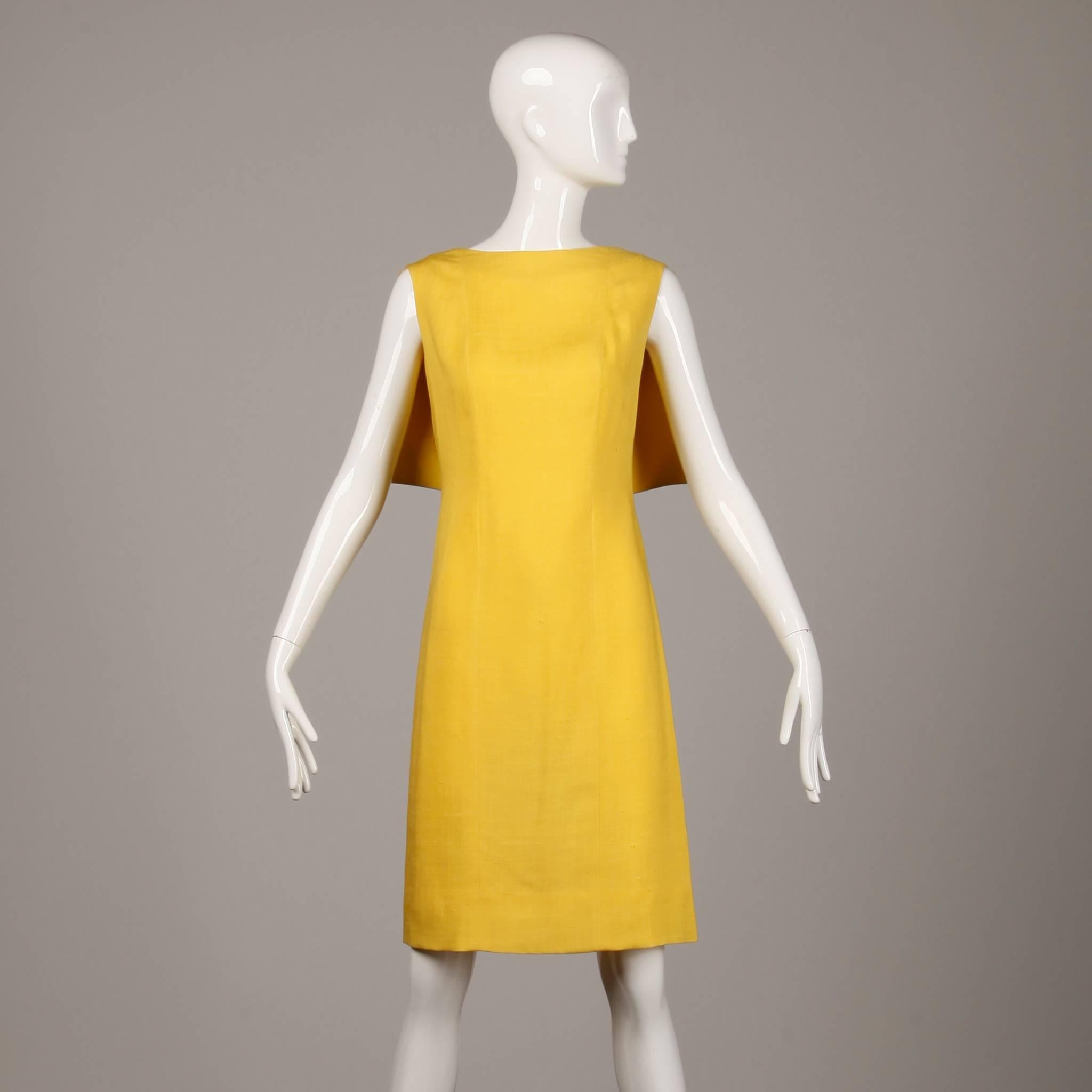 Bright yellow vintage 1960s sheath dress with rear cape detail by Pauline Trigere. Fully lined in silk with zip, hook and tie back closure. The bust measures 35", waist 27.5", hips 35", total length 38.5". There is a seam