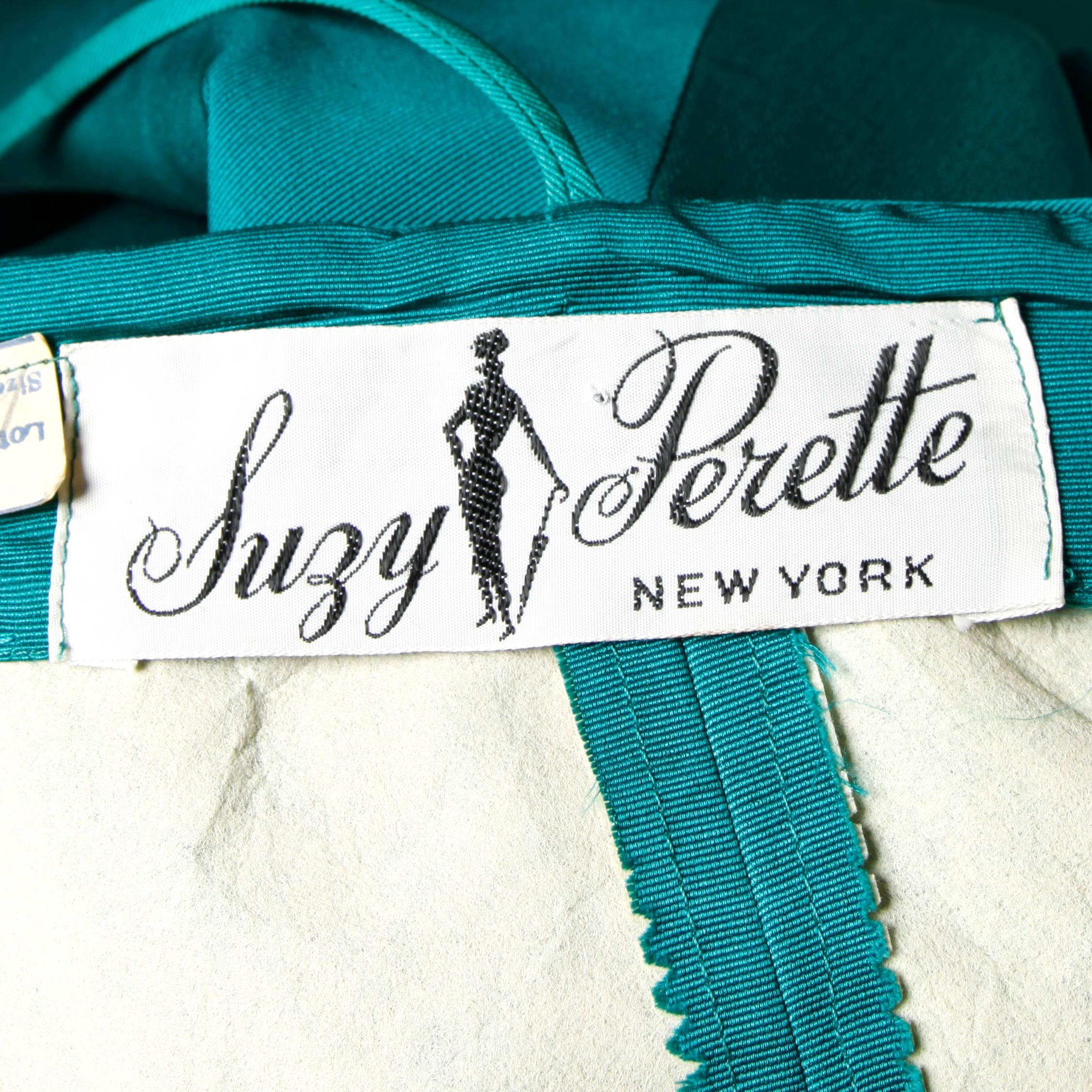 Stunning and unique emerald green silk taffeta dress with an origami bubble hem by Suzy Perette. Bow detail at the bottom and hourglass silhouette. Fits like a modern size small. Please see measurements below.

Details:

Unlined
Back Metal Zip and