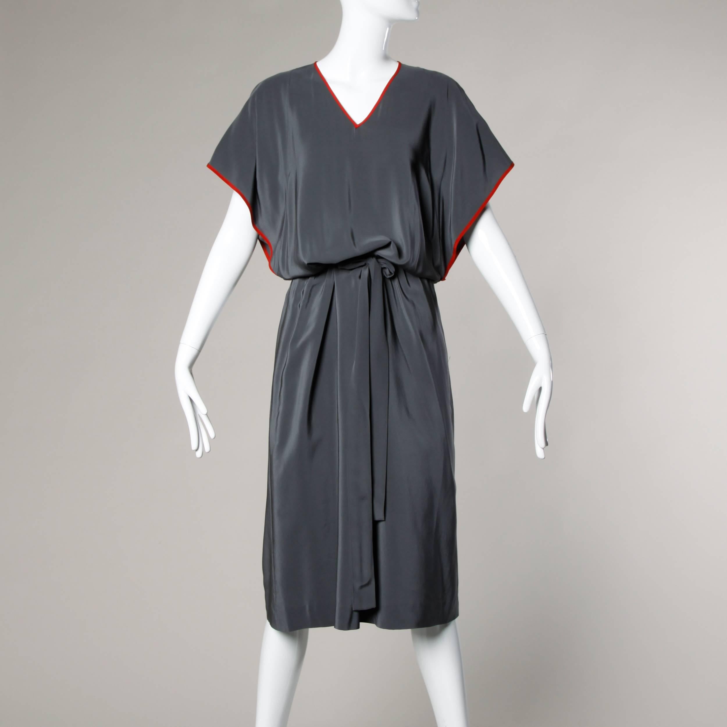 Chic avant garde dress by Guy Laroche in creamy gray silk with red silk trim. Unique draped cut with removable long sleeves and ruffled shoulders. V-neckline and matching sash.

Details:

Unlined
Side Pockets
Matching Sash
Marked Size: F 42/