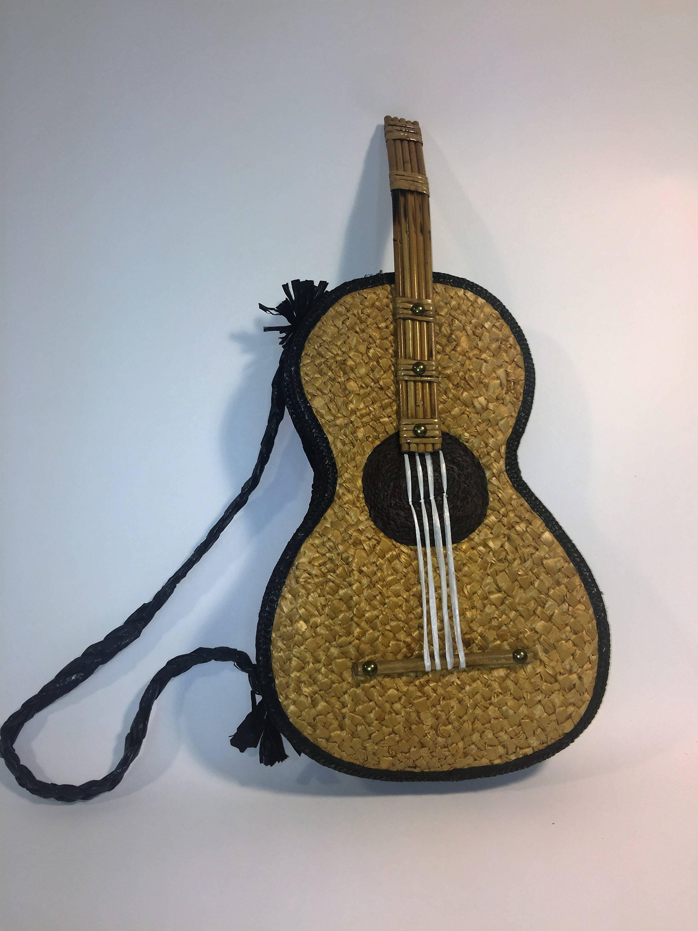Full Size Guitar Raffia Handbag with Bamboo Handle and Fretwork 
 and Brass Studs designed in the 1950's-1960's in the United States. Designed with a Brass Zipper and a Black Fabric lined Interior.In very good vintage condition with some age