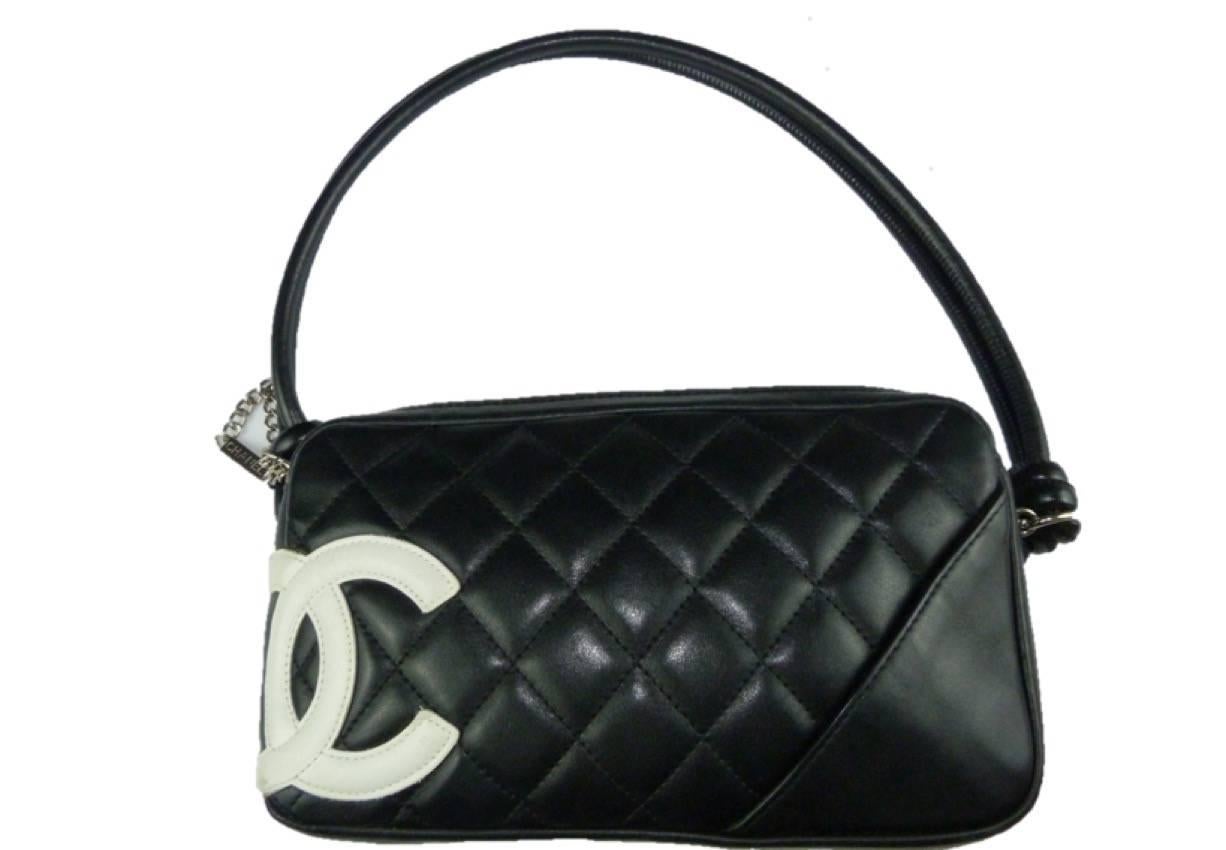 Gorgeous black quilted mini Chanel Cambon shoulder bag
Black quilted leather with white leather CC and black handles. 

Silver Chanel branded zip pull. 
One inner zip pocket. 
Bright pink satin interior / Hologram image

22cm width, 14cm high