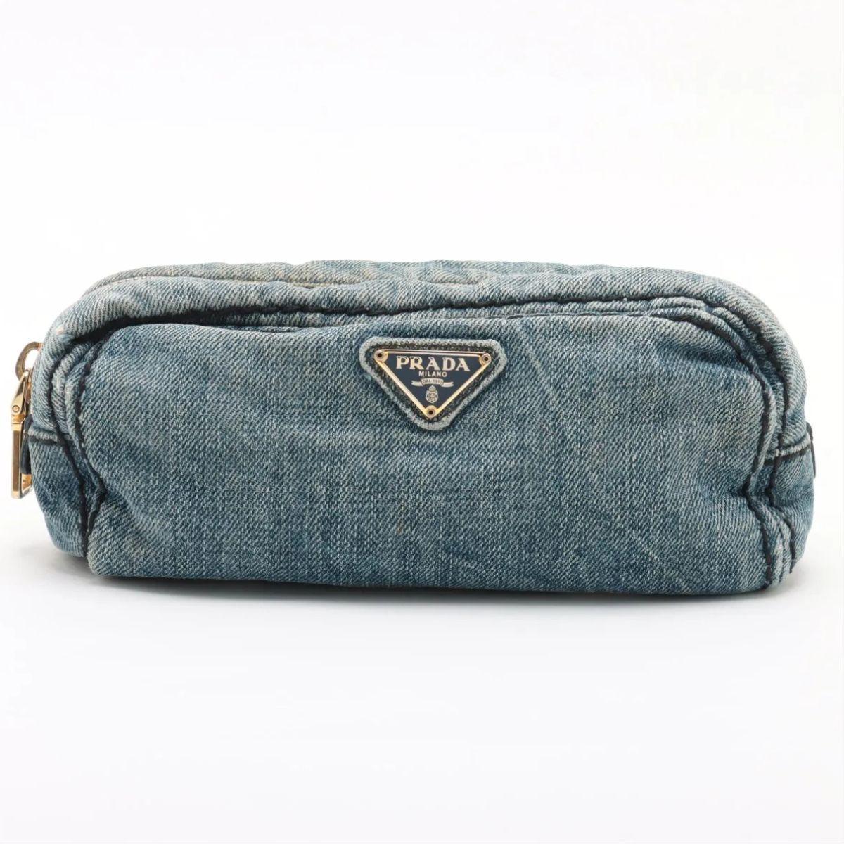 La Bolsa vaquera Prada en azul muestra el minimalismo moderno de la marca con un toque desenfadado. Confeccionada en tela vaquera resistente y ligera, la bolsa presenta una elegante silueta rectangular ideal para organizar tus objetos esenciales. El