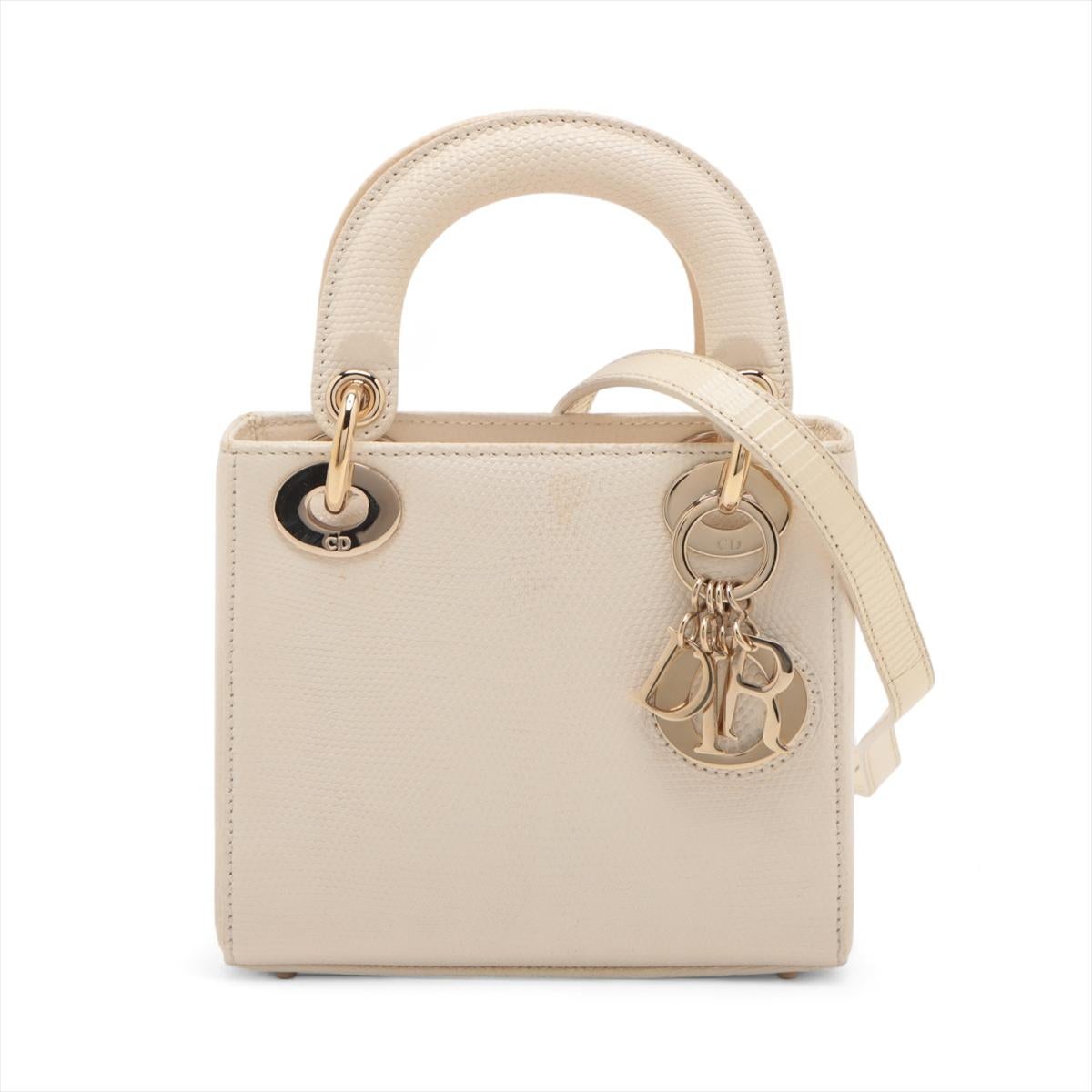 Le mini-sac à main en lézard Lady Dior de Christian Dior, en ivoire, est un accessoire luxueux et élégant conçu à partir d'une peau de lézard exquise, qui témoigne de l'engagement de la marque à l'égard d'un savoir-faire raffiné. Doté de