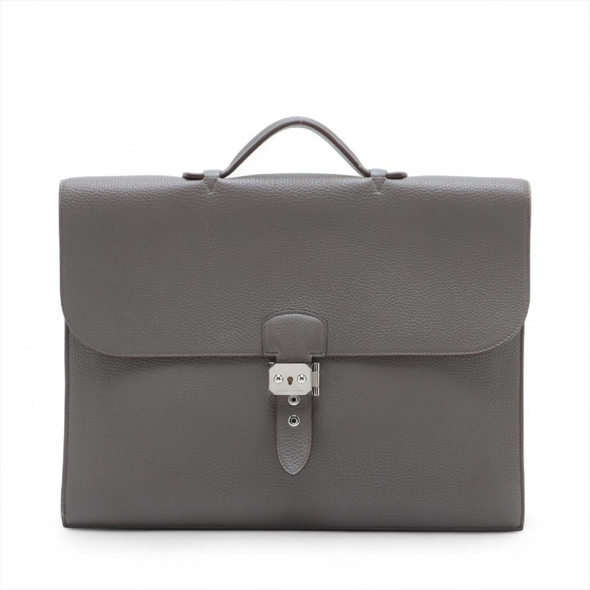 Le Sac Depeche 38 d'Hermès en cuir Taurillon Clémence dans la teinte Eleg est un sac à main raffiné et sophistiqué, conçu pour être à la fois élégant et pratique. Confectionné en cuir souple grainé Silhouette, il présente une silhouette structurée