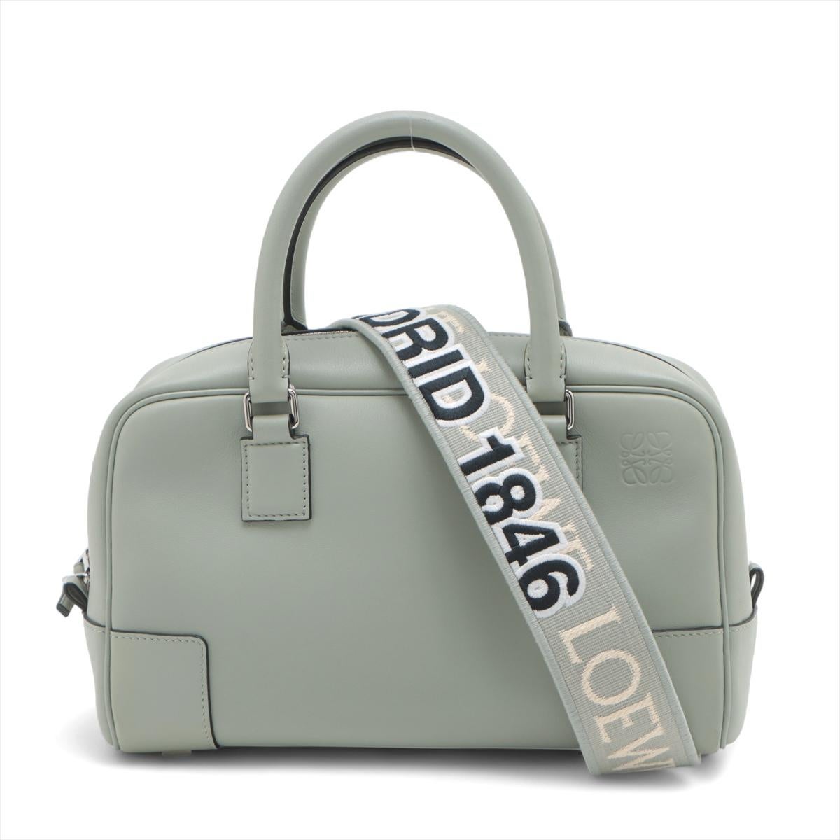Le sac à main en cuir Loewe Amazona 23 en vert Sage est une réinterprétation raffinée d'une icône des années 1970, célébrant son 50e anniversaire . Réalisé en cuir de veau nappa souple, ce sac compact et polyvalent est doté d'une fermeture à