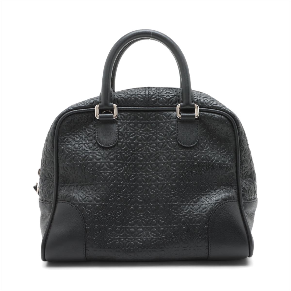 Le sac à main en cuir Loewe Amazona 75, de couleur noire, est un accessoire sophistiqué et spacieux qui allie harmonieusement un design intemporel à une fonctionnalité moderne. Confectionné en cuir de veau noir de première qualité, il est orné du