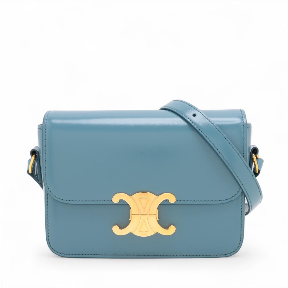 Die Celine Teen Triomphe Lederumhängetasche in Blau ist ein raffiniertes und elegantes Accessoire, das aus hochwertigem Glattleder gefertigt ist. Das kultige Triomphe-Logo auf der Frontklappe verleiht ihr einen Hauch von Luxus. Die Umhängetasche mit