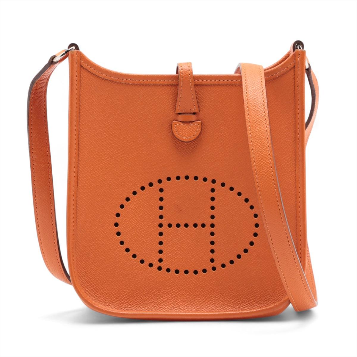Die Hermès Evelyne 16 TPM aus Veau Epsom-Leder in der kultigen Orange-Nuance der Marke ist eine kompakte und dennoch überraschend praktische Crossbody-Tasche. Trotz seiner geringen Größe bietet er einen durchdacht gestalteten, geräumigen Innenraum,