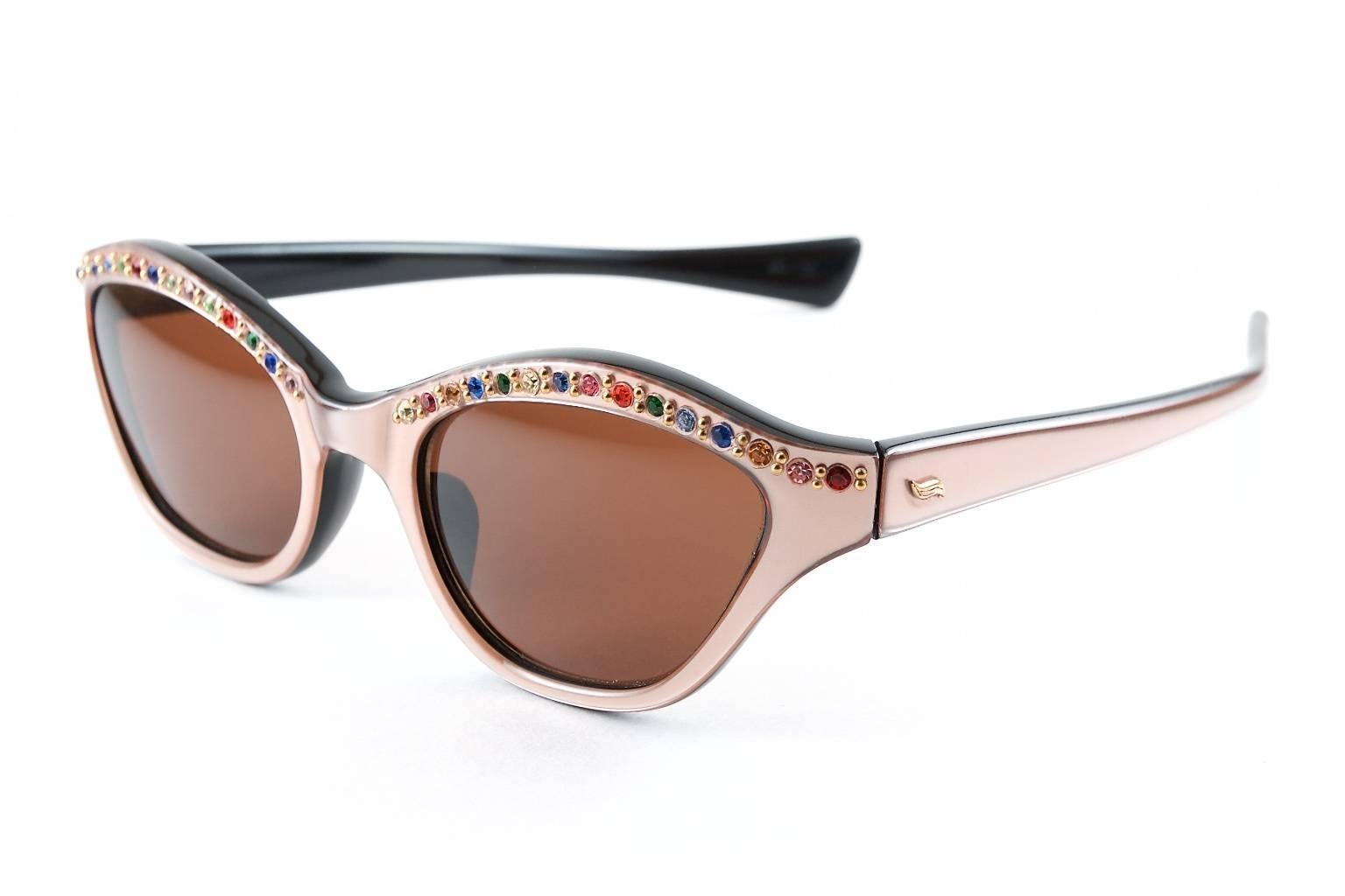 New old stock 1950s pink satin over black French multi colored rhinestone sunglasses give you a uniquely shaped, more rectangular variation to traditional 50's cat eye sunglasses that is guaranteed to draw attention most every time you wear them.
