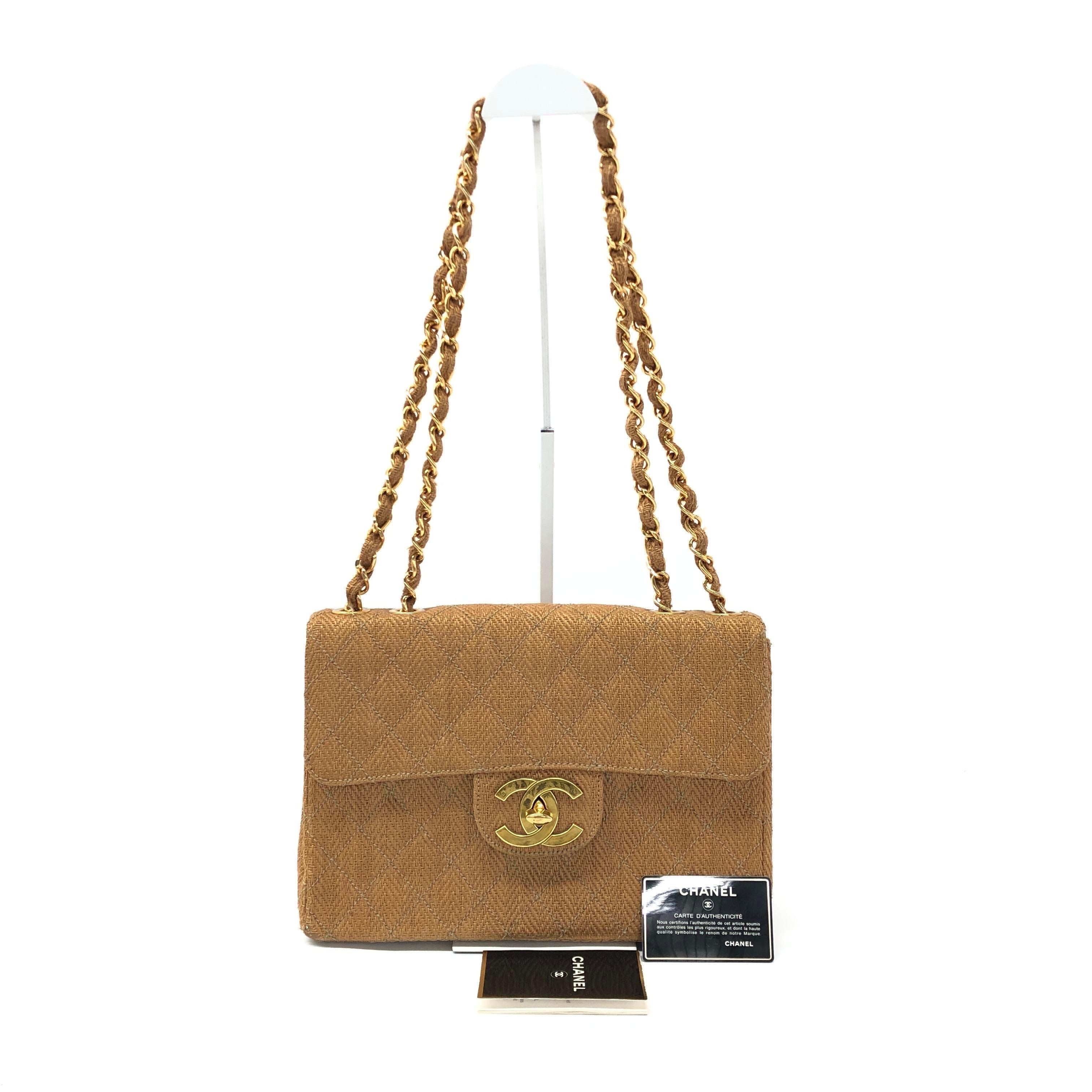 Découvrez l'élégance intemporelle avec le sac à bandoulière Chanel Classic Flap Maxi. Réalisé en toile de raphia tressée marron rare et avec des accessoires plaqués or 24k, ce sac époustouflant exsude la sophistication. Le grand logo CC emblématique