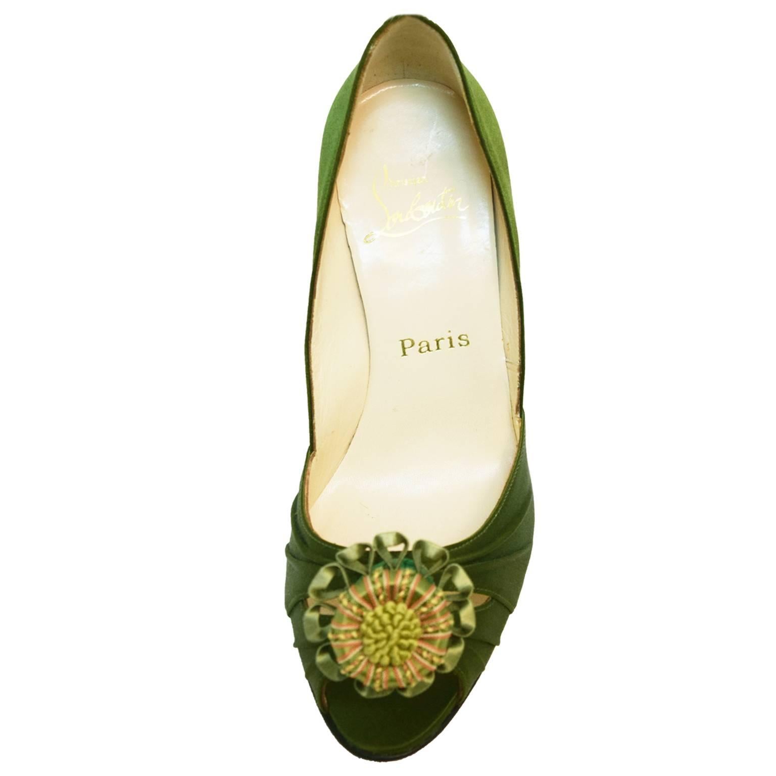 These exotic Christian Louboutin Peep-toes are covered in full olive silky satin, with gathering detailing on the toe box. Hand stitched Florette embellishment is elegantly placed on the toe box for an overall beautiful look. Red bottom Sole, and