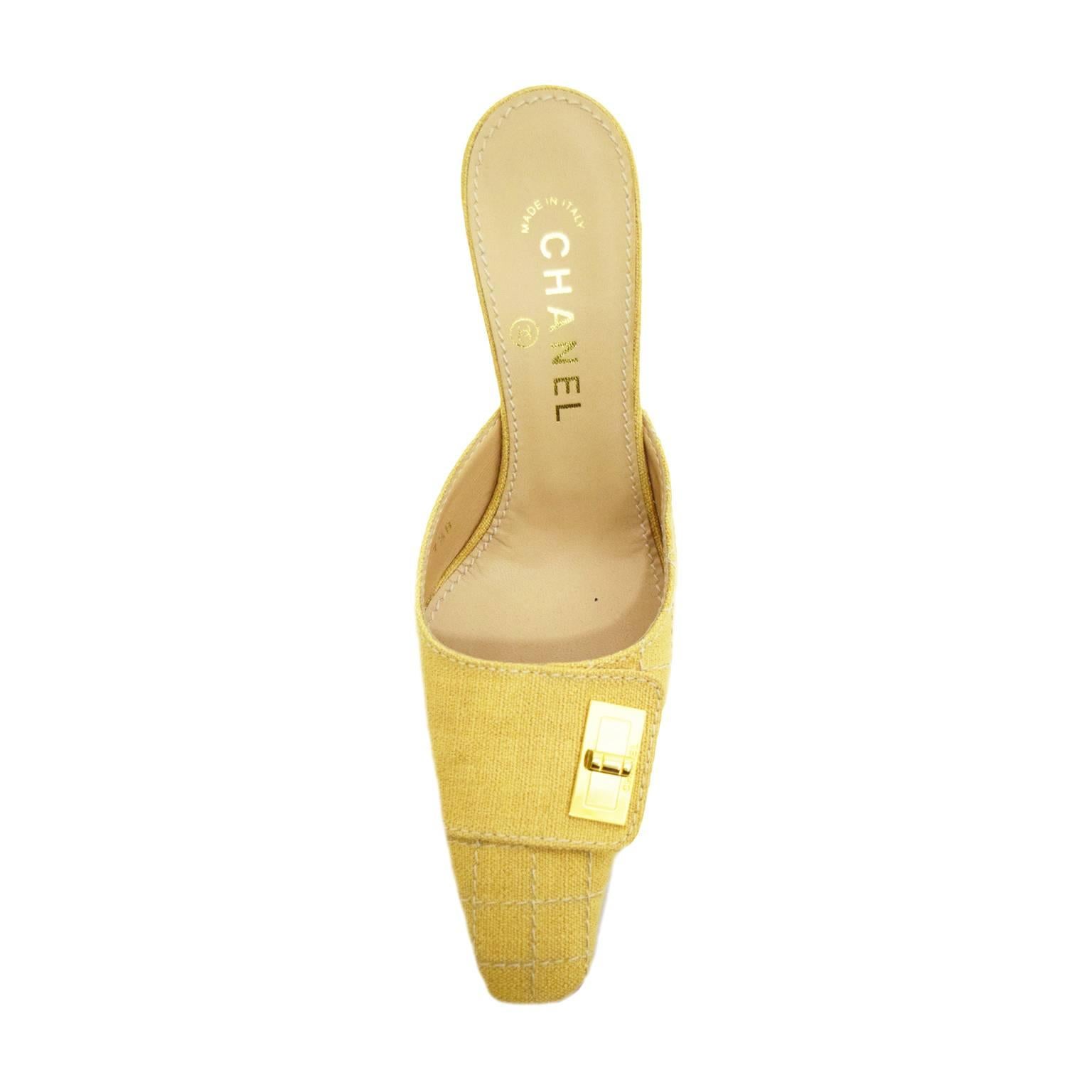 These classic Chanel mules are incased in a simplistic mustard and white woven tweed and have a top strap and gold hardware buckle for embellishment. Nude insole with 3 inch cuban heel.