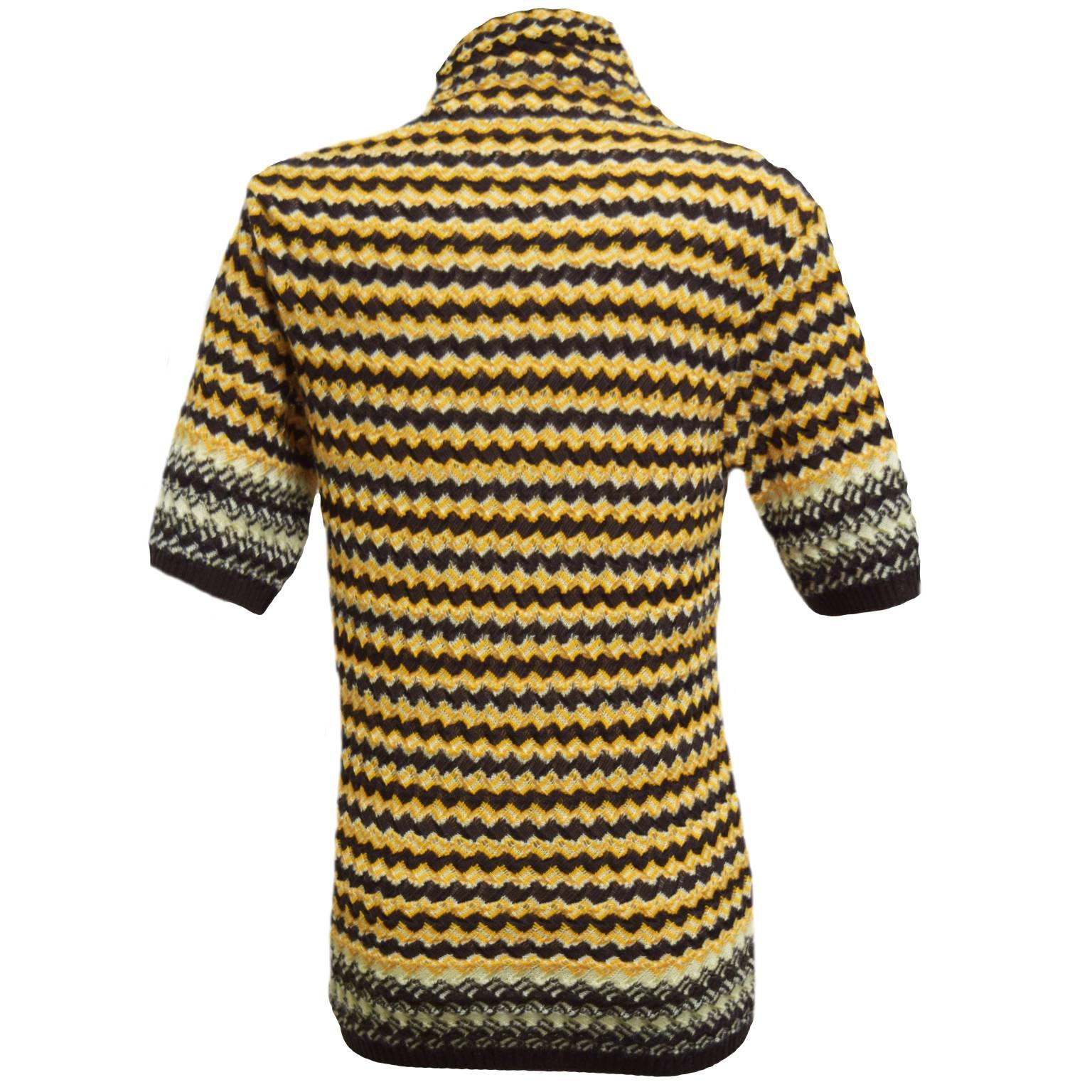 This Missoni knit blouse is the exact image of the brand. Made out of 100% cotton this top is a brown, cream, and mustard chevron print taking the look back to the 70's type of aesthetics. High neckline and short sleeved.