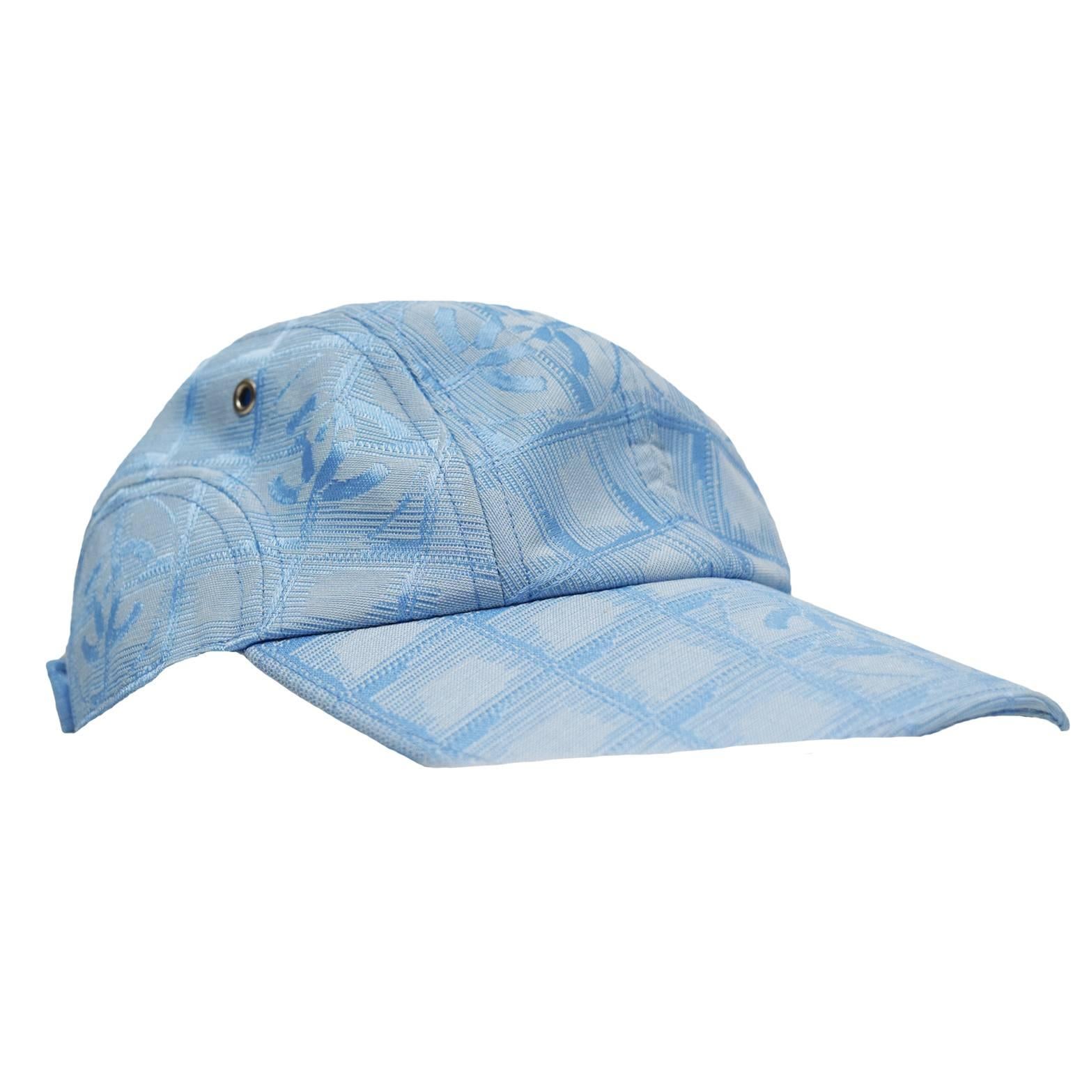 This Chanel cap is a ice blue canvas blend with silk monogram print. Adjustable strap located in the back with CC metal logo buckle.