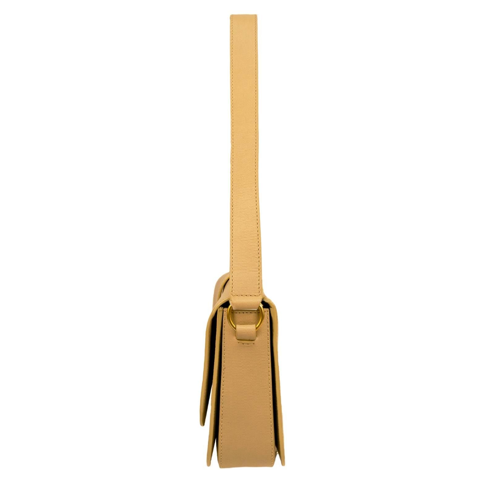This beautiful Yves Saint Laurent shoulder handbag is a rich neutral camel leather and has a front closure flap. The shoulder strap is thick leather for strength and comfort and is a 9 inch drop. The front buckled includes a Y sculpted in