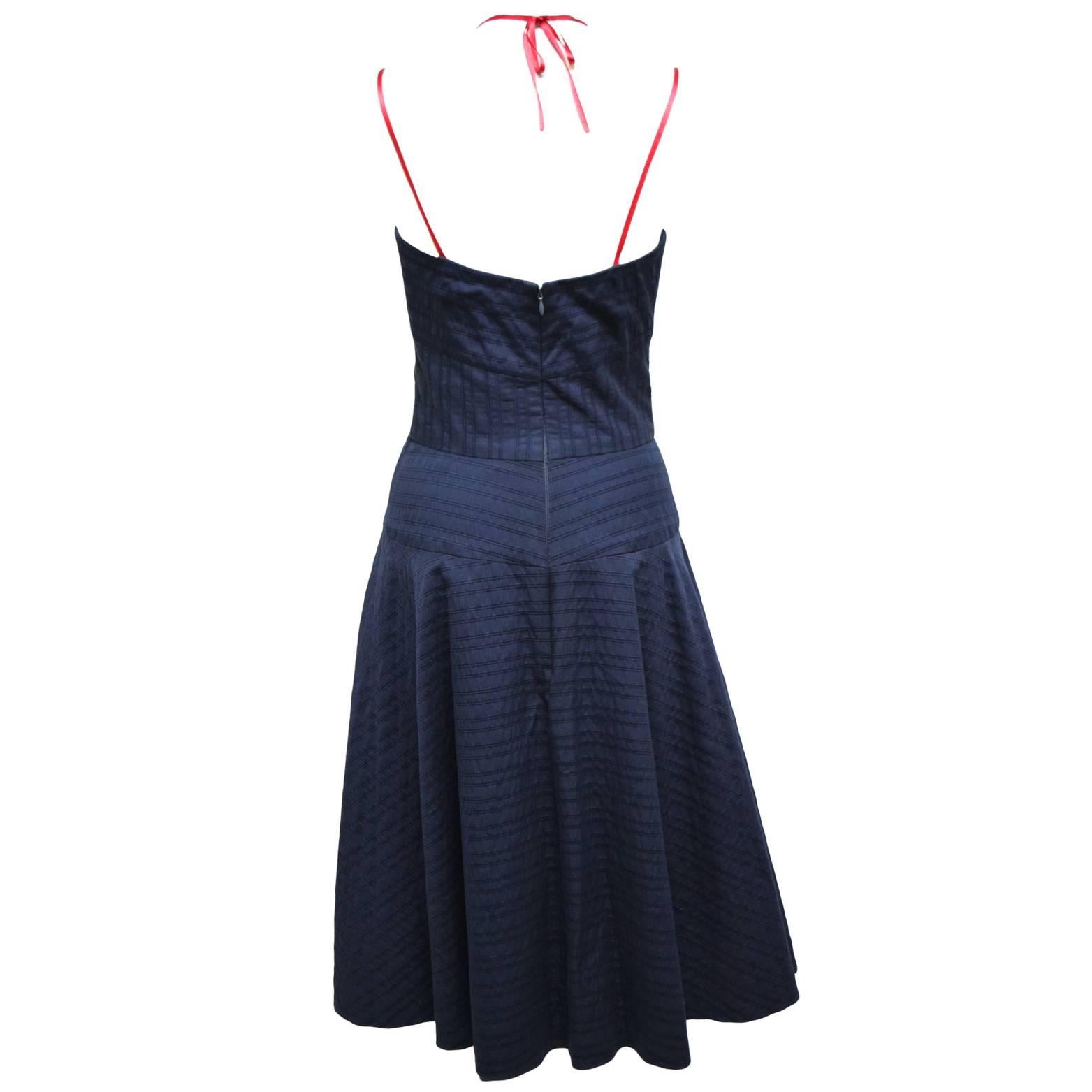 This dress by Carolina Herrera is a fun playful sweetheart bust dress with a flared skirt. Pleating details are throughout the whole dress. The straps are gross grain red ribbon and create a halter silhouette.