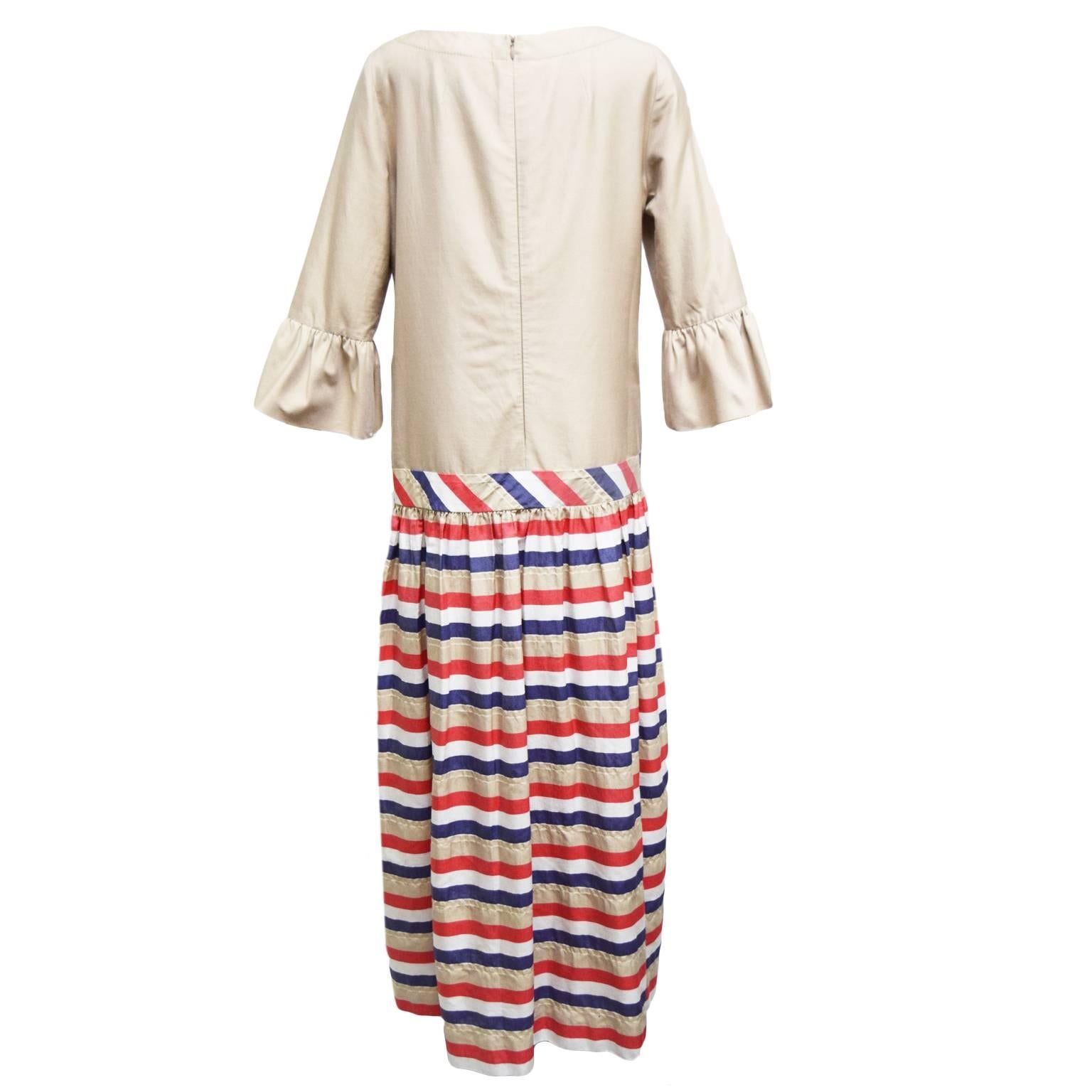 This dress by Algo is made from 100% rich cotton. The blouse of the dress is beige and has flared three quarter sleeves. The back is zipped and the skirt is striped and full, the length ends at the ankles.