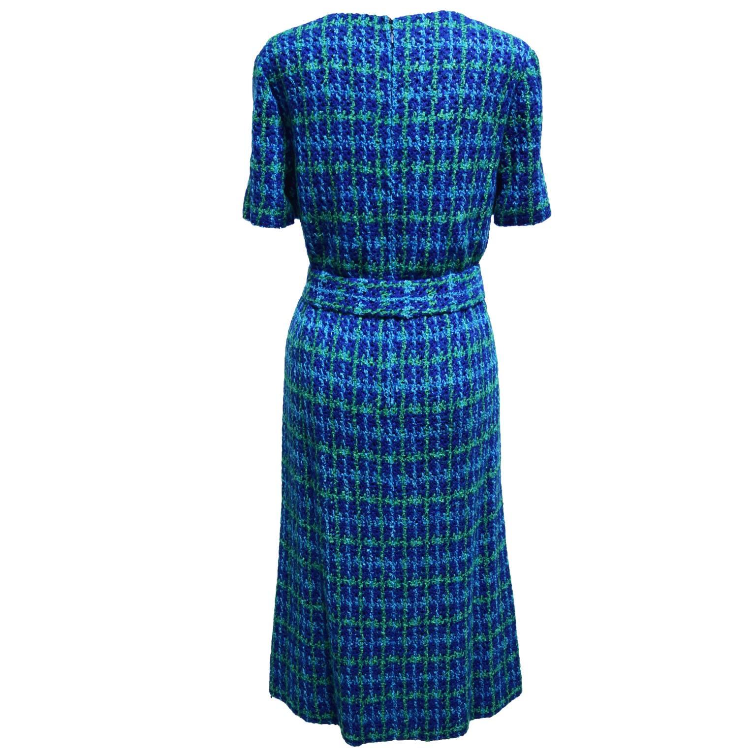 This dress and jacket ensemble is completely crocheted in Portugal. The jacket has blue button closures and two front pockets. The dress is a short sleeved V-neck sheath dress.