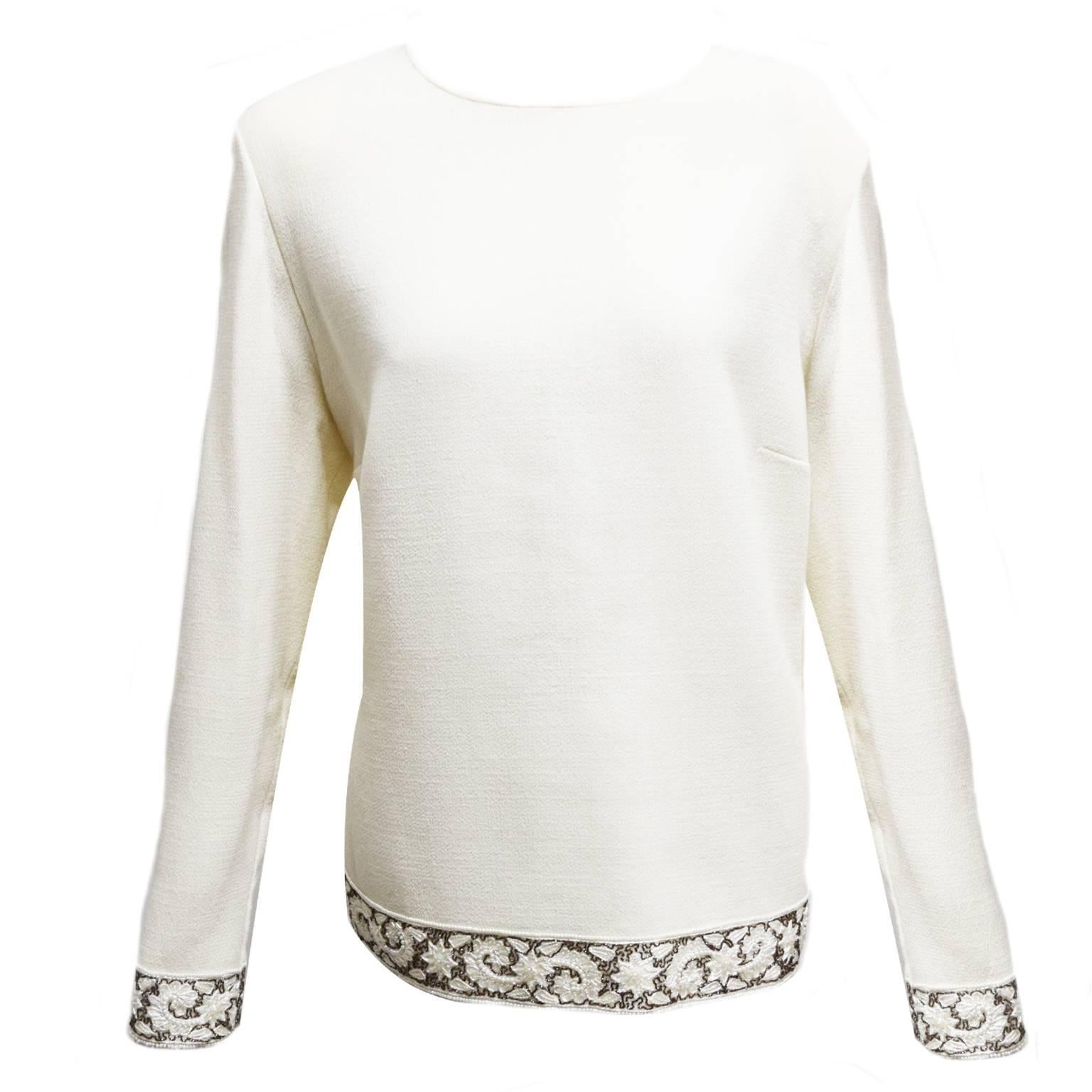 This Aurora Ruffolo and Christian Ruperto two piece skirt ensemble is made from a rich ivory wool. The blouse has a keyhole back and the skirt has a side zipped closure. The blouse and skirt both have a beaded stitched floral border at the bottom of