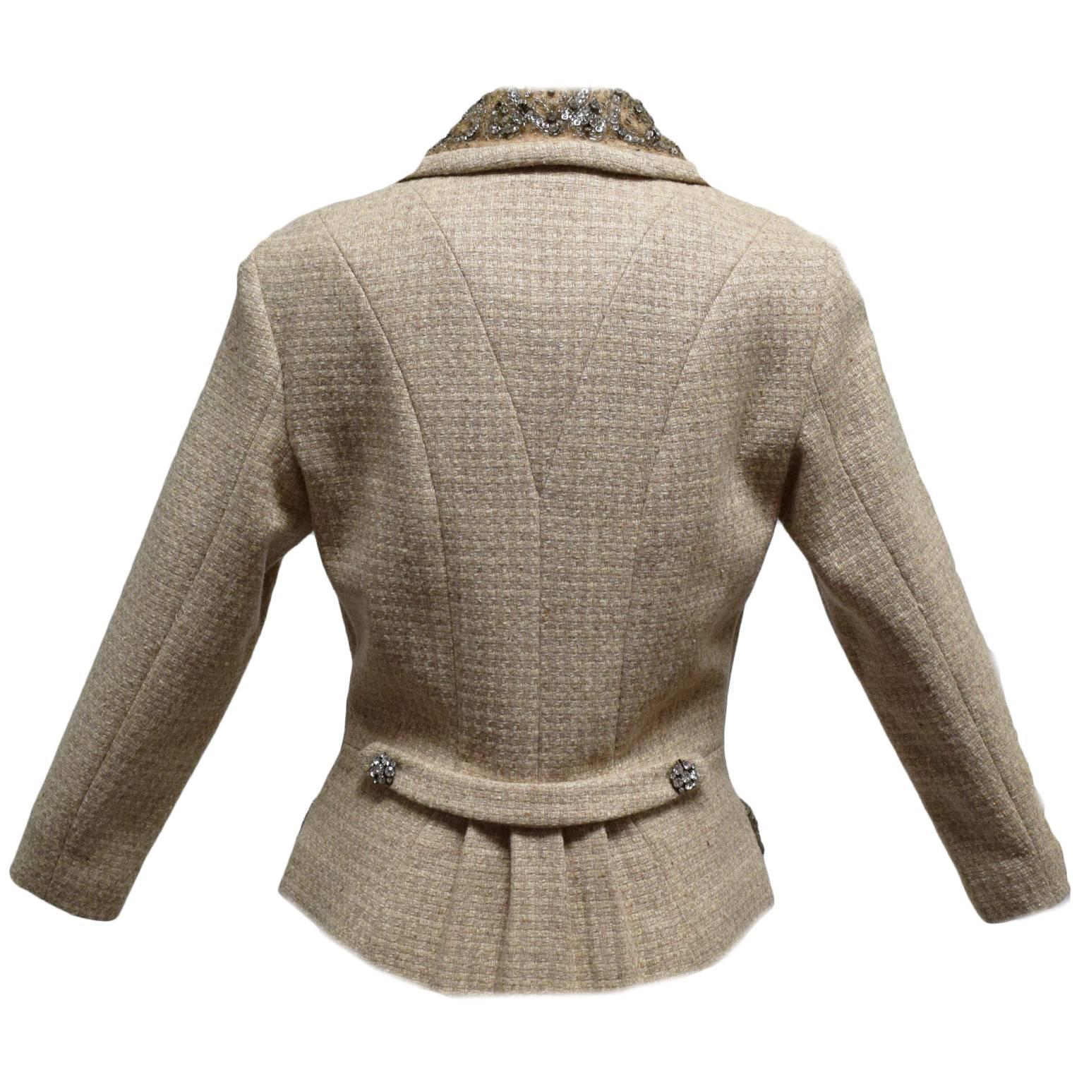 This Tracy Reese jacket is made of 100% beige wool. The jacket is fully lined in silk and has crystal brooch like button closures. The pockets, collar, and sleeve ends are incased in lace, seed glass beading, and crystals for an elegant contrast. 