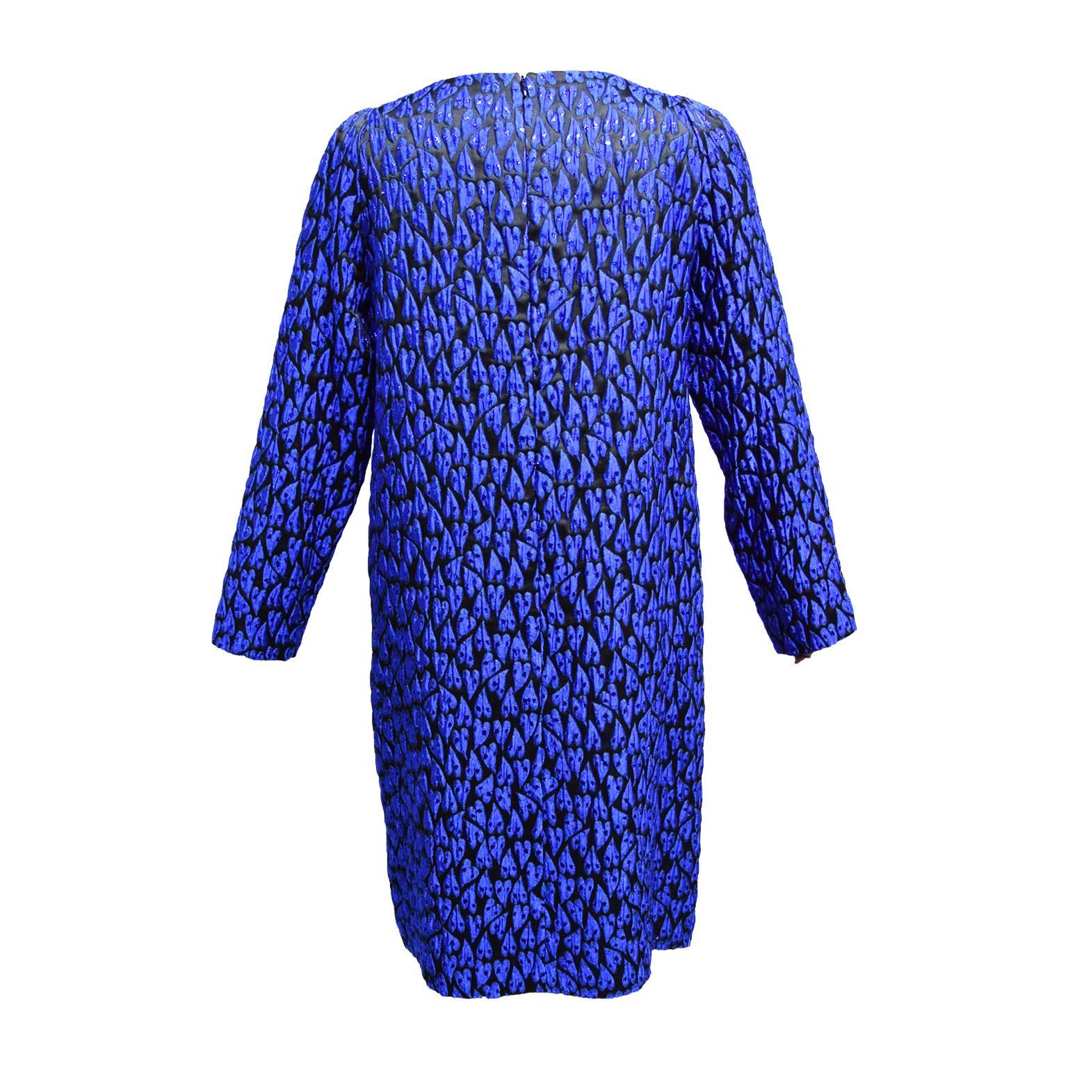 This Mauro Grifoni shift dress is made out of acrylic. The dress is printed with blue shaped hearts and gives off an iridescent sheen. The dress is long sleeved and has a back zipped closure. The dress is fully lined and has a scoop neckline. 