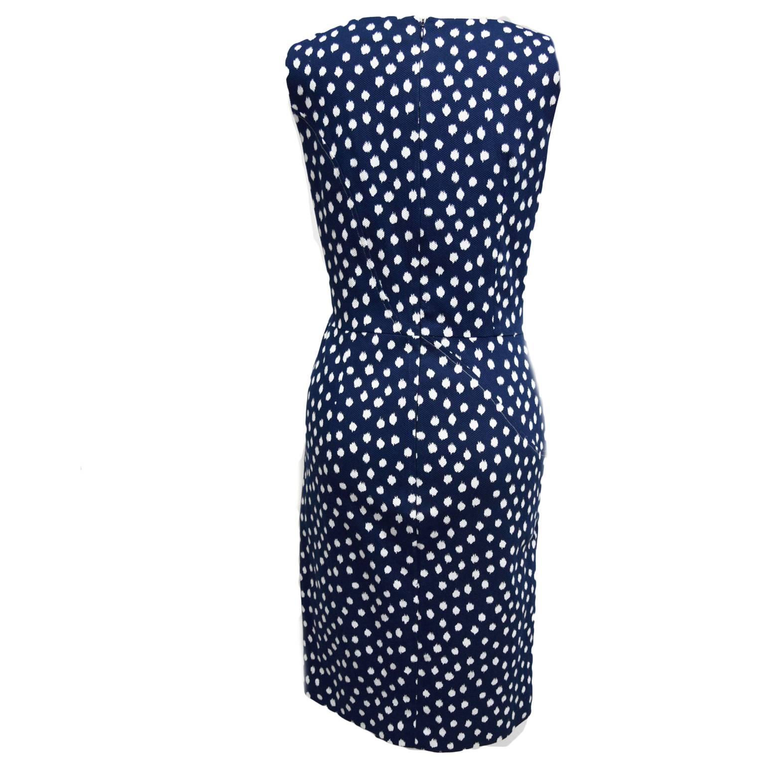 This Oscar de la Renta dress is 100% cotton. The neckline is a scooped neckline and the bodice has a wrapped gathering detail. The material is a navy and white printed abstract polka-dot print and the dress is fully lined with a zipped back closure. 