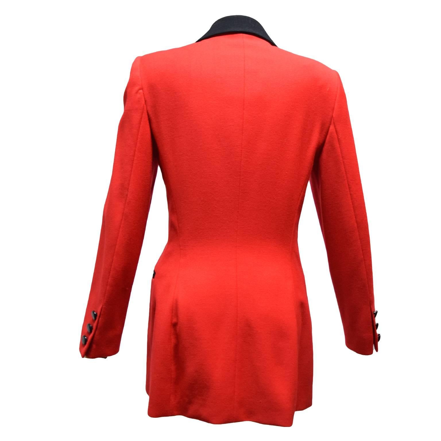 This Escada jacket is made of 100% wool and is red with black wool trimming. The jacket is fully lined in red silk and has two side knife pleated pockets and round button closures. 