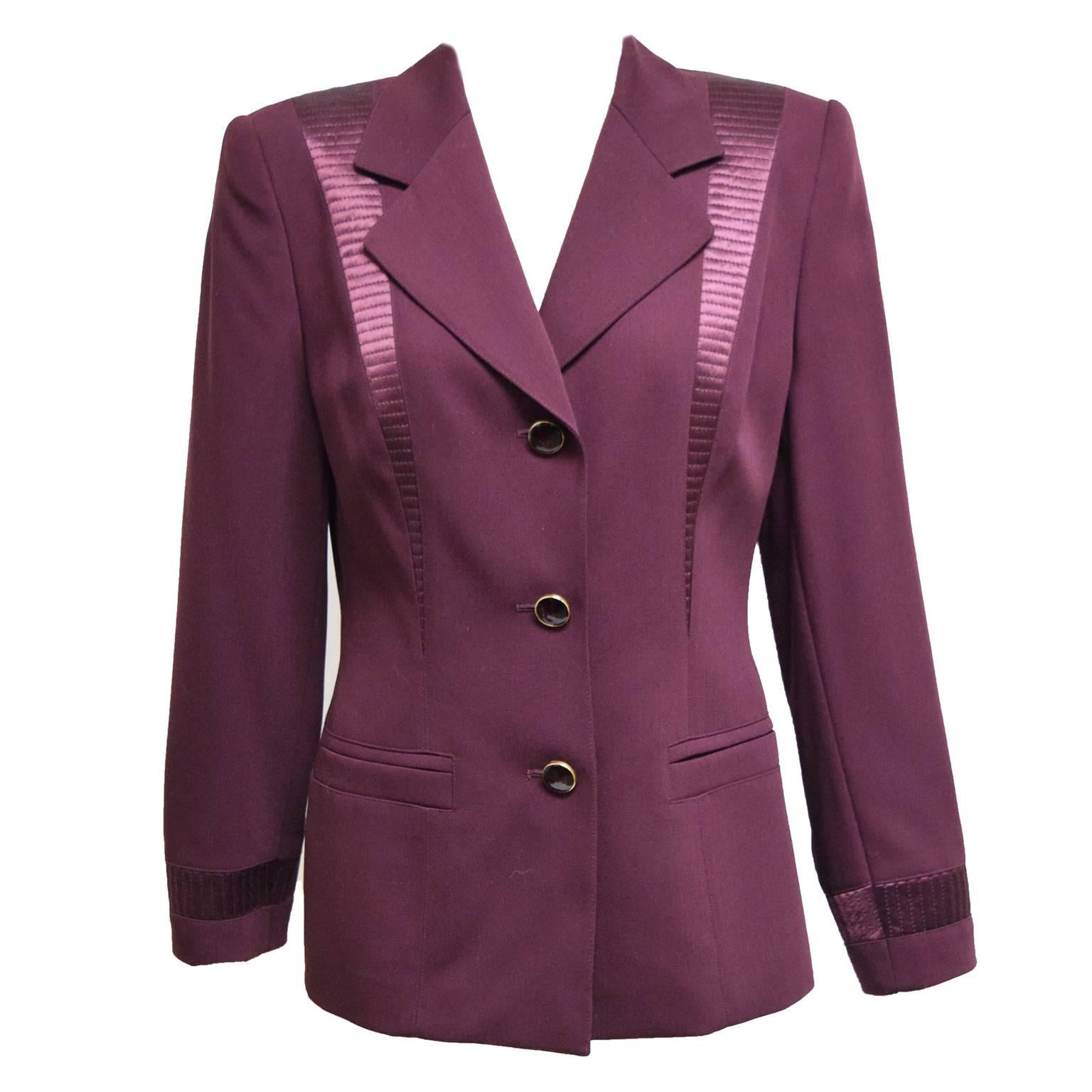 This vintage two piece skirt suit by Escada is a classic. It is made of a merlot wool and lame silk. The skirt is a knife pleated skirt with alternating silk and wool panels. The jacket is fully lined in silk and has ruby jewel like stone button