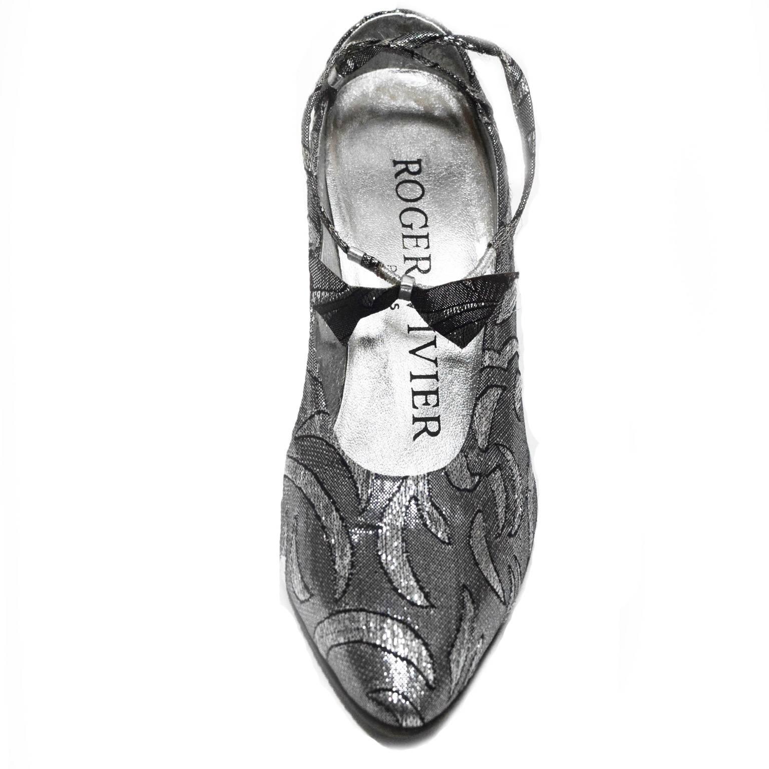 These classic Roger Vivier kitten pumps are made out of silver and black brocade in a tribal print. The ankle strap has a brocade like bow embellishment, great for any evening occasion. 