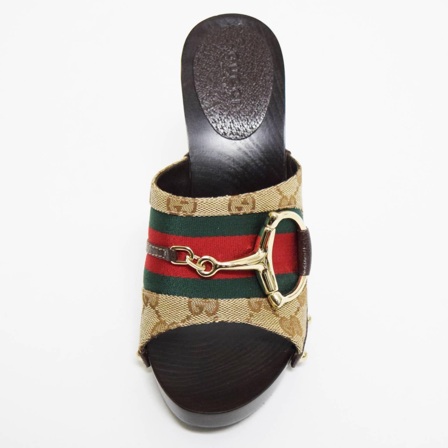 This appealing mules by Gucci have a dark wooden sole, canvas covered leather upper with original Gucci print and signature green and red striped detail. There is a gold metal buckle located on the upper as well and gold metal grommets on both sides