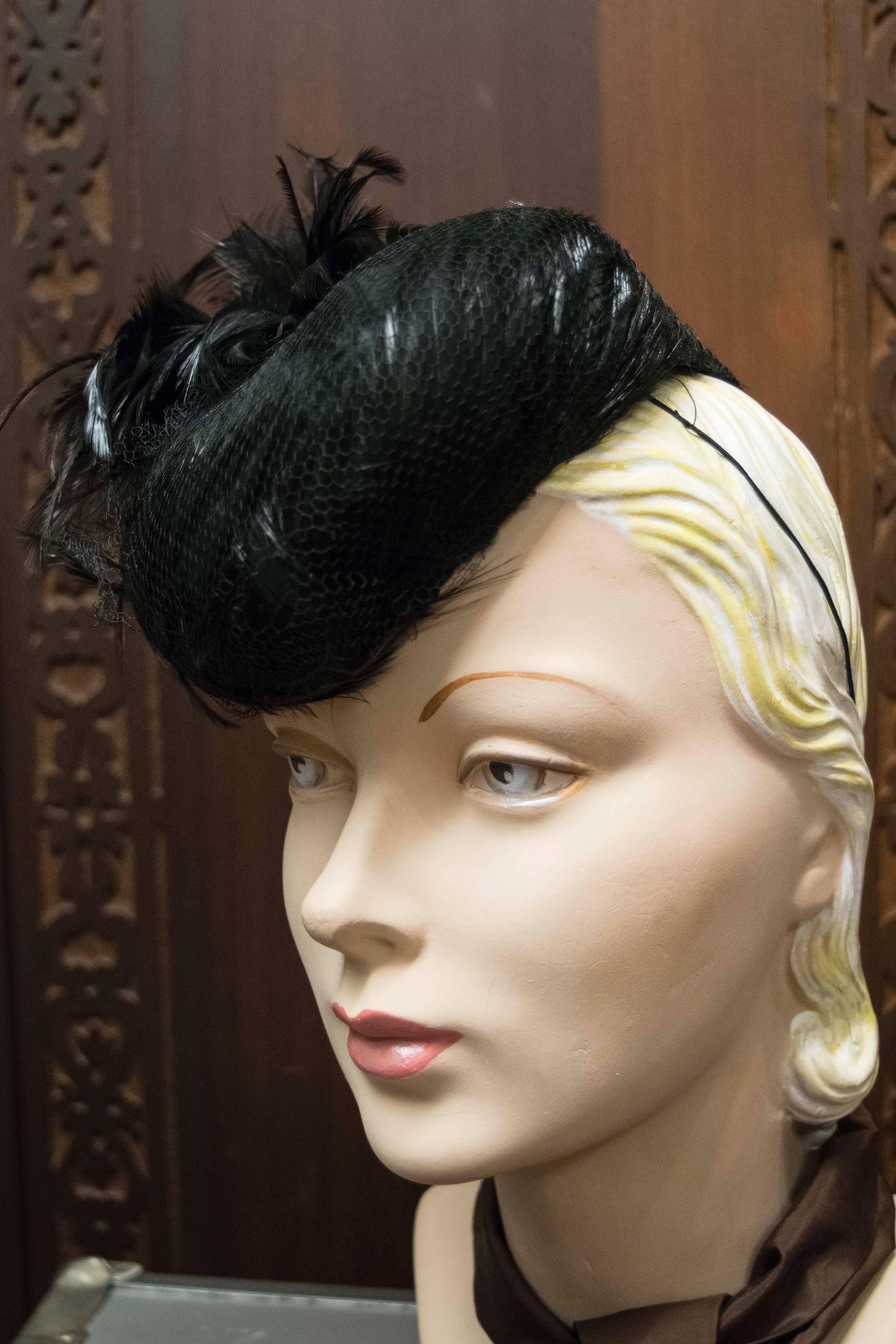 1940s Feather Cocktail hat

Stunning example of 1940s millinary made from moulded feathers encased in original netting, with additional feather plume and elastic strap.