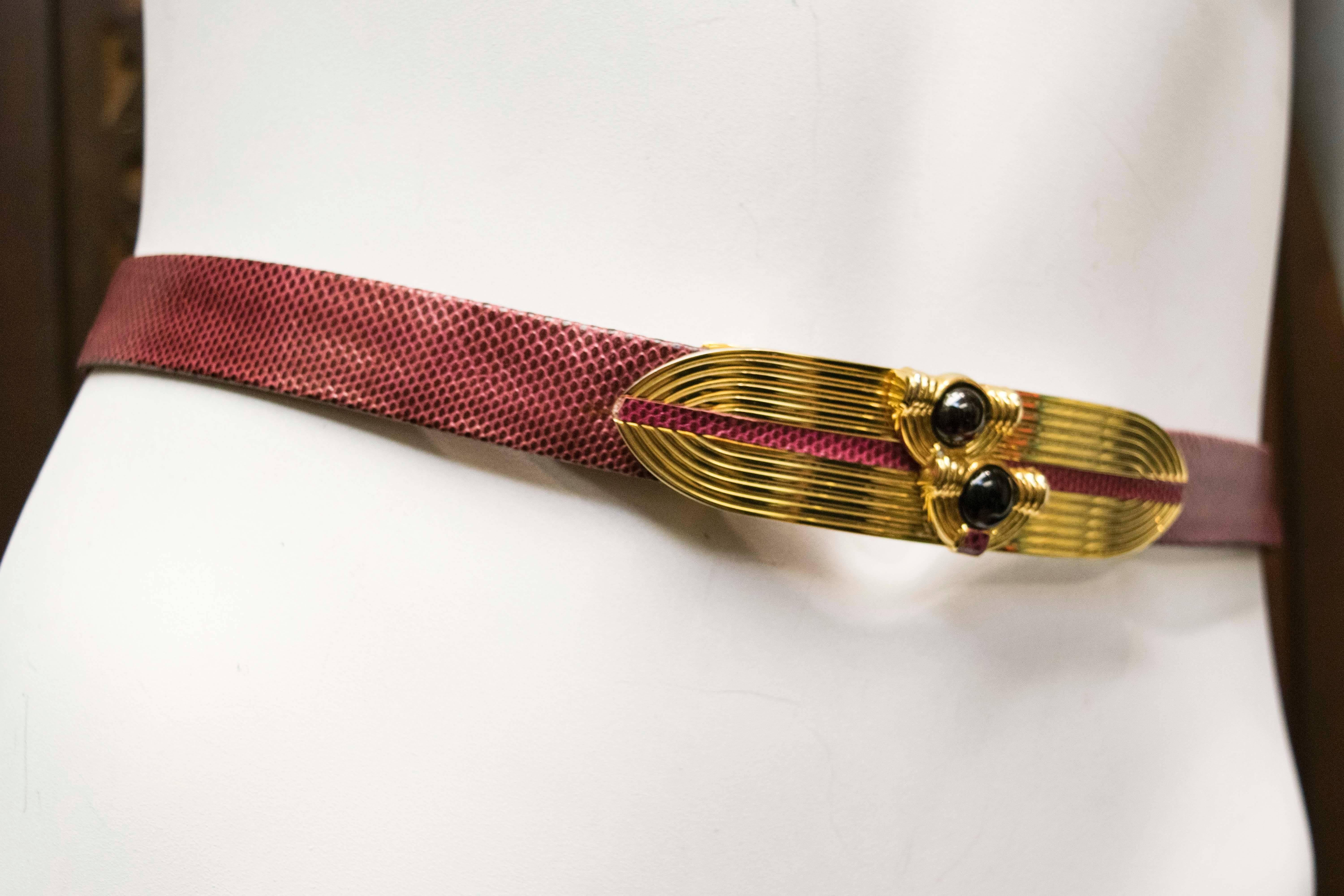 1980's Judith Leiber fully-adjustable belt made in maroon lizard skin, with modernist gold tone belt buckle with two set-in glass beads, one black and one dark maroon. Hook and eyelet closure. 

Measurements:
Waist: 23