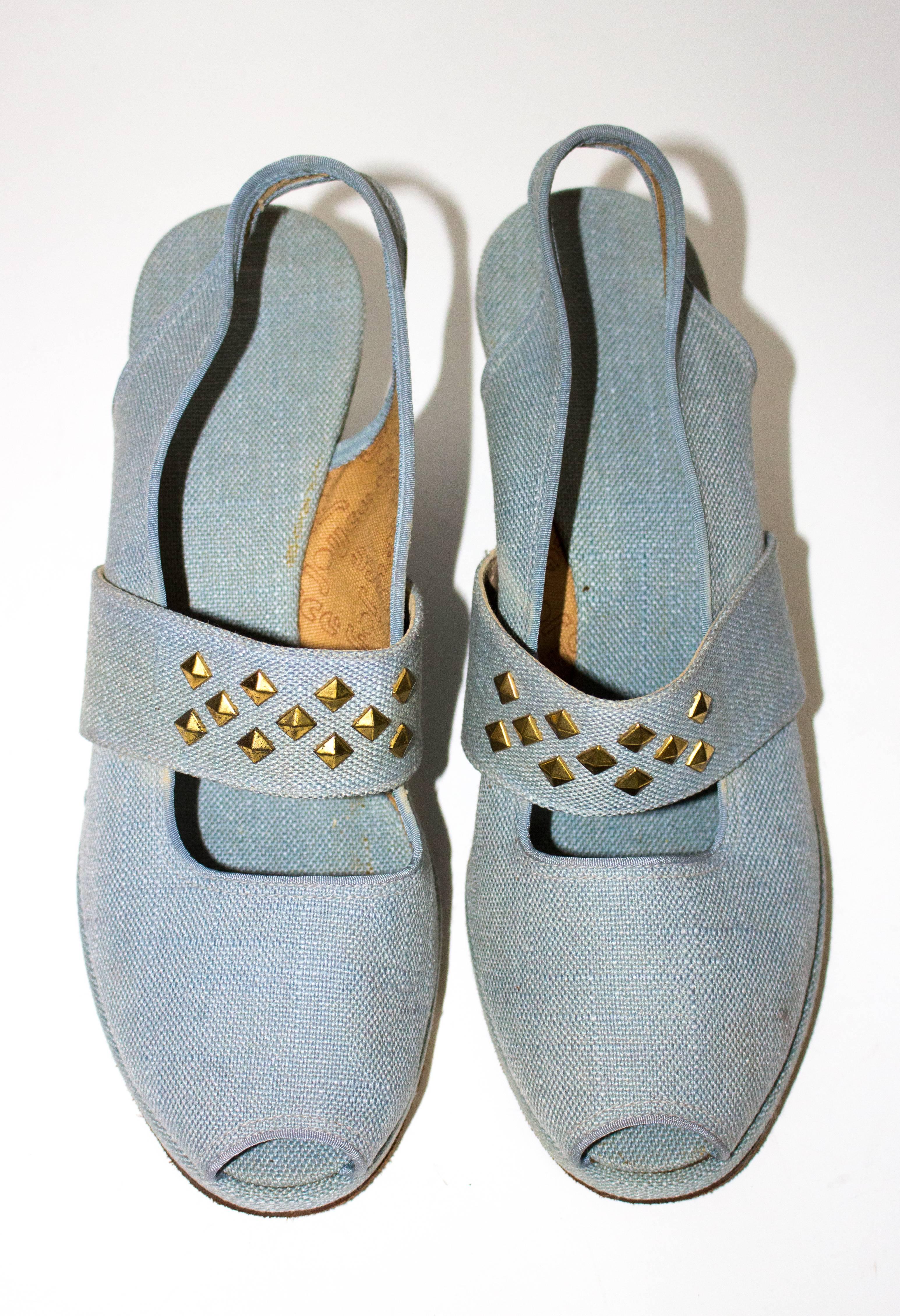 1940s wedges in a light denim-tone wash. Peeptoe slingbacks. Elasticated front strap embellished with gold tone studs. Canvas insole. Suede leather sole. Comes with original advertisement. Never worn!

Insole: 9 3/4"
Palm of foot: 3