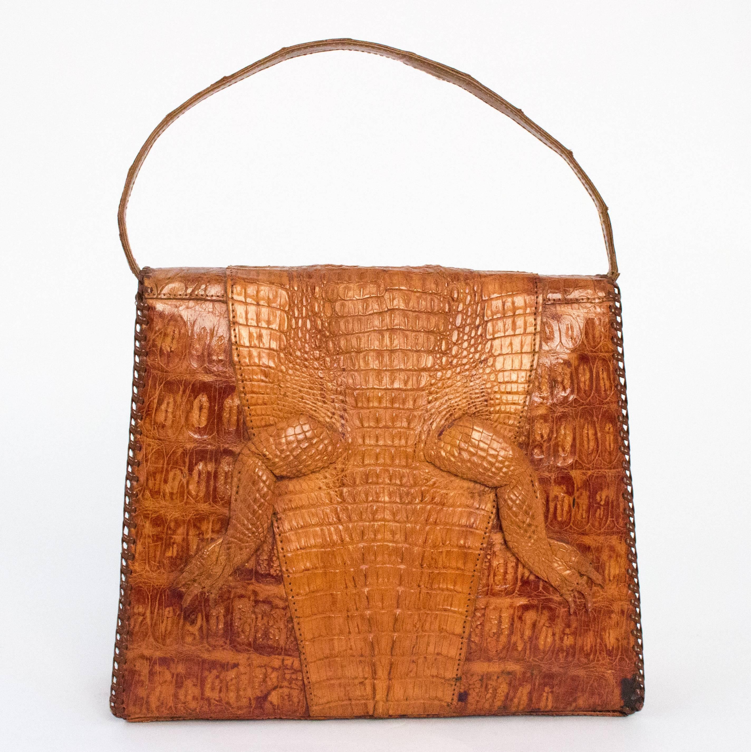 40s Alligator handbag. Snaps closed. Glass eyes. One interior zippered pocket. Whipstitch edging. Made in Cuba. 

Measurements:

Width: 9 - 9.5