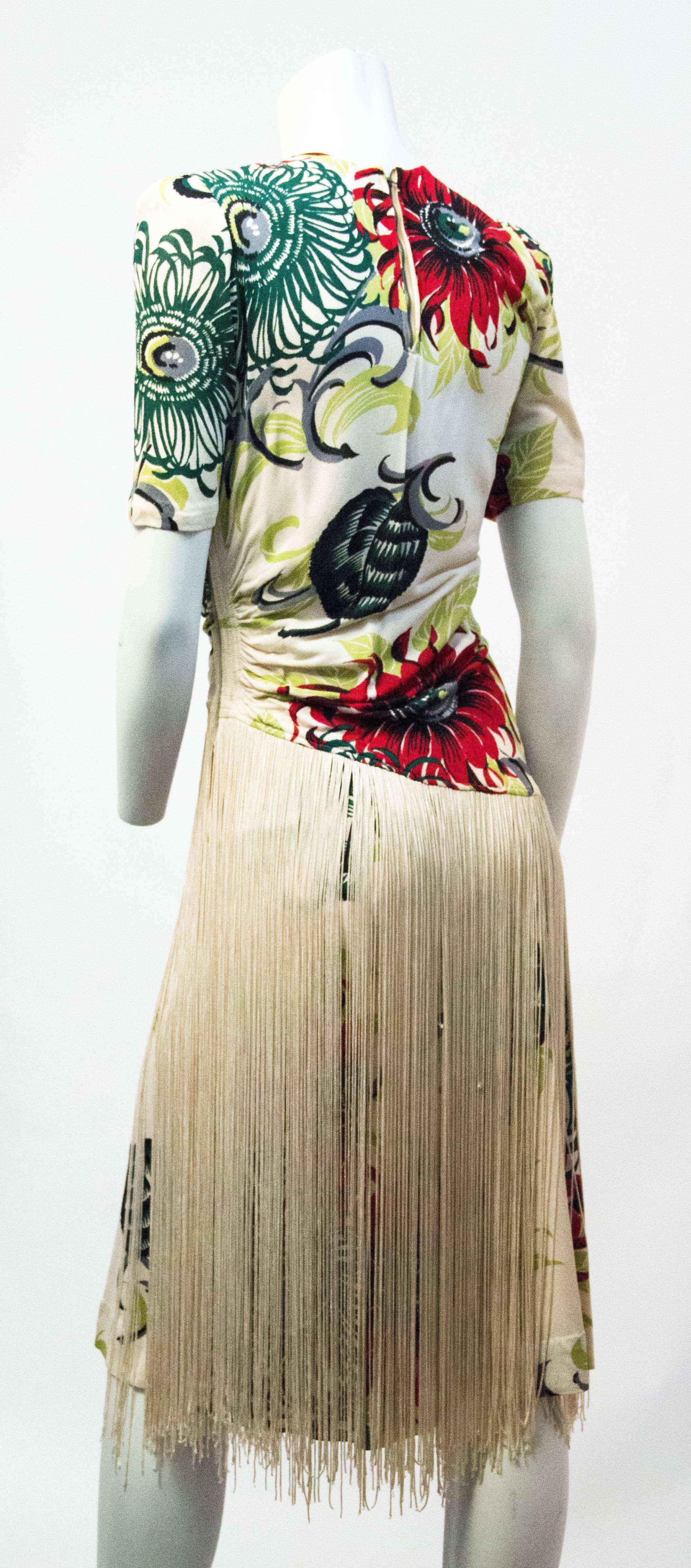 40s printed silk crepe cocktail dress. Exotic floral print. Ruched shoulders and left side. Single layer of long rayon fringe layered over skirt. Left side has 8 inch gold tone Talon zipper mid way through the bodice. Lined in strong mesh scaffold