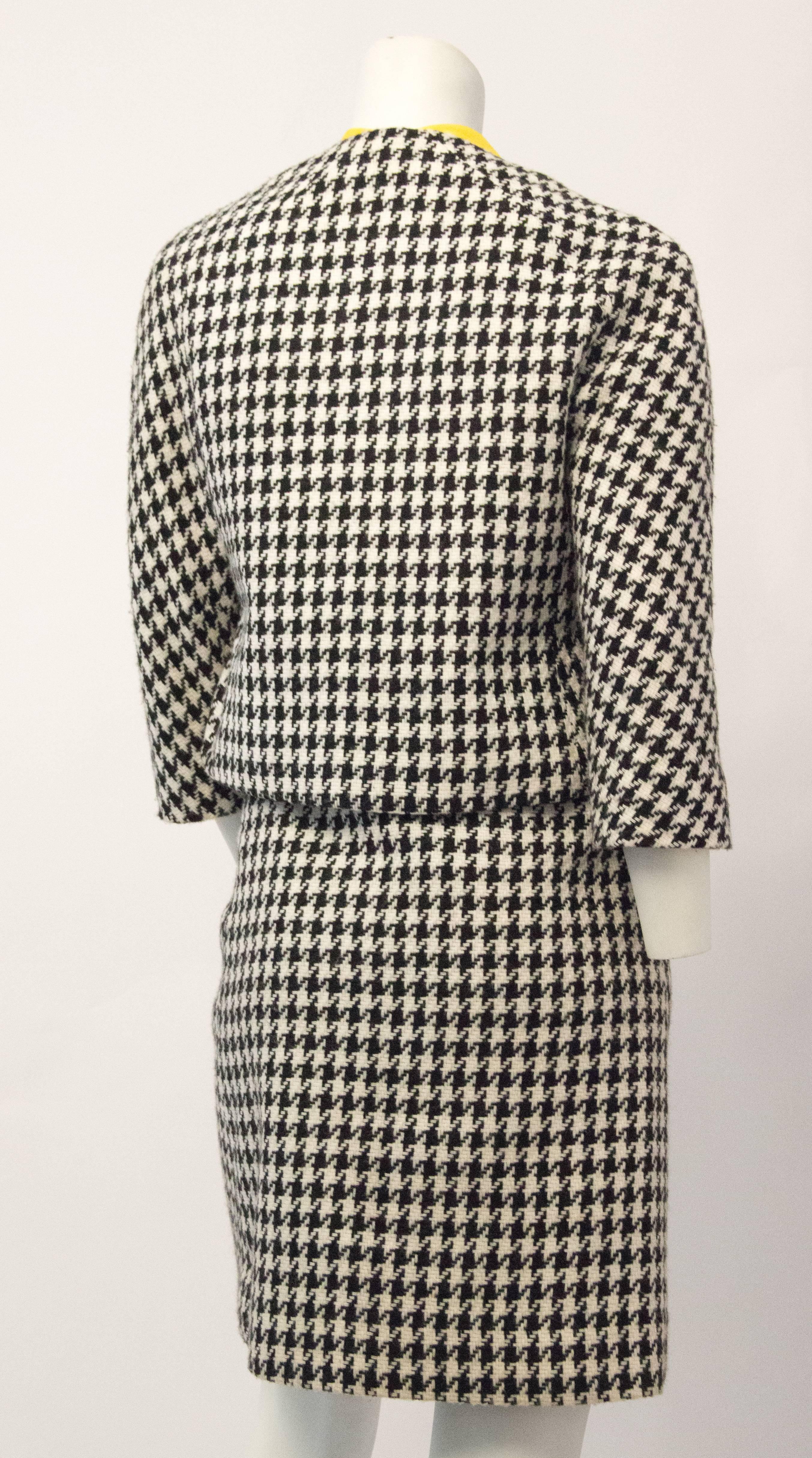 60s Joseph Magnin houndstooth suit with original matching yellow sleeveless blouse. Jacket is lined, and buttons up the front. Mock flap pockets. Fitted blouse buttons up the back and ties at the neck. Skirt is lined and zips up the left side. 

