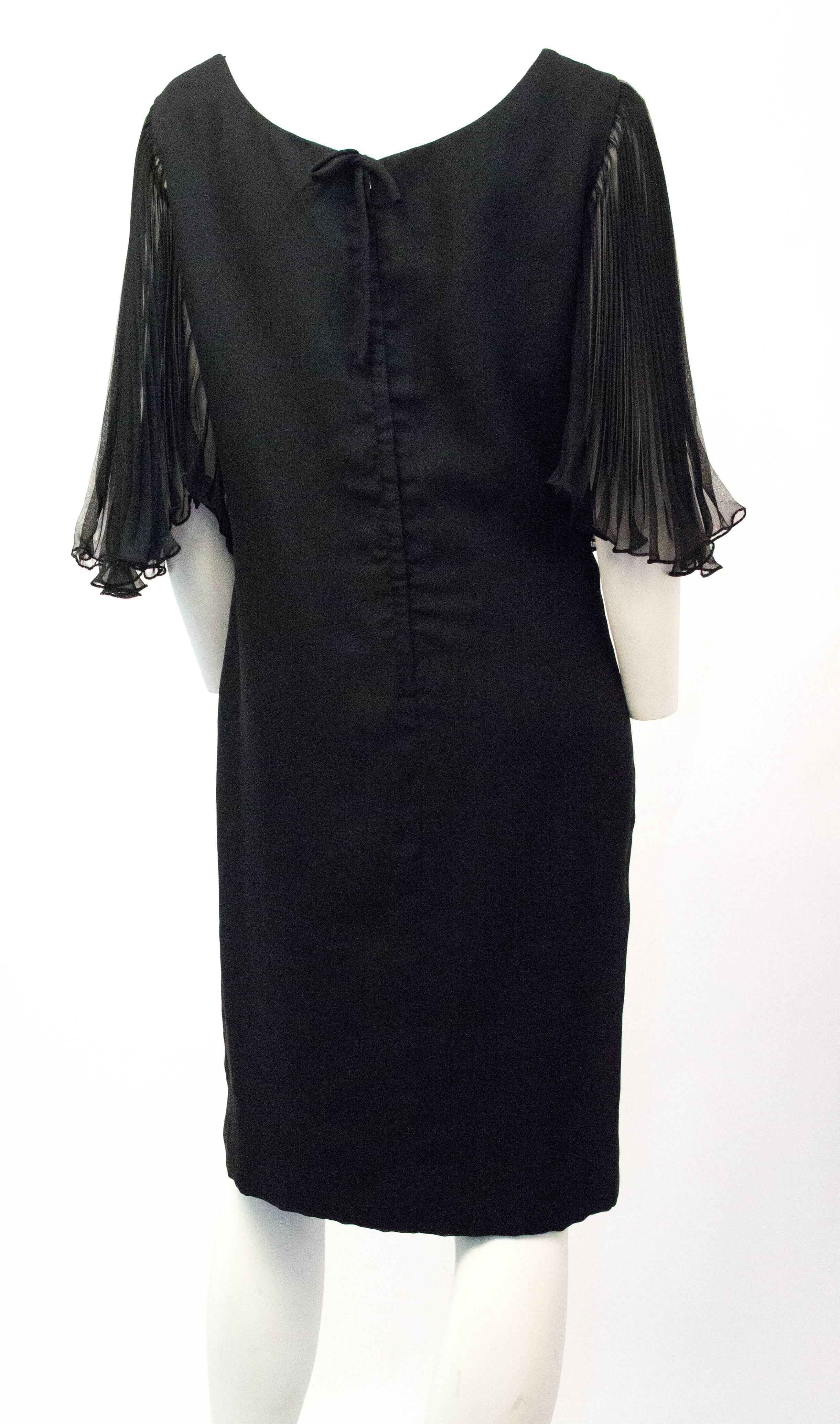 70s Miss Elliette black cocktail dress with pleated chiffon butterfly sleeves. Body of dress is made from one layer of acetate with two over layers of chiffon. Fully lined. Metal zipper up the back. 