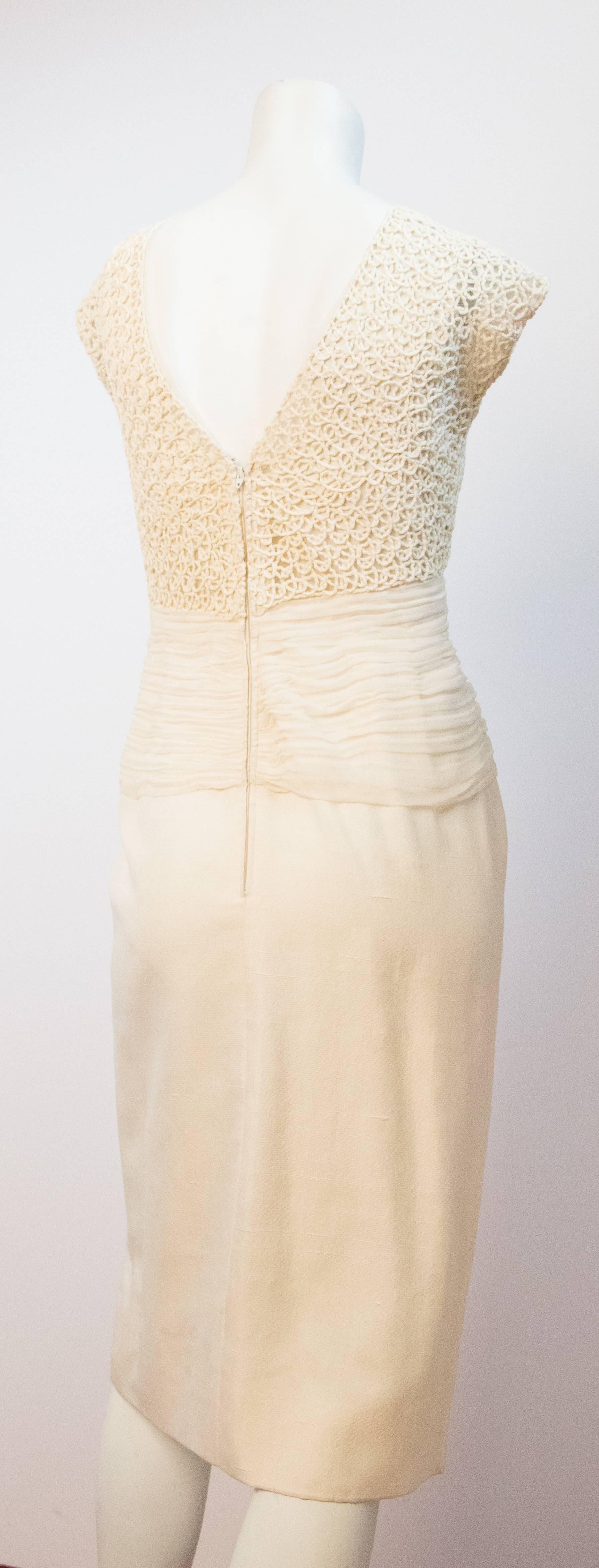 60s cream silk sheath with silk chiffon touching along the bodice. Ribbon type work makes up the upper bodice and sleeve of the dress. Nylon zipper up the back. Filly lined in organza and mesh. 

